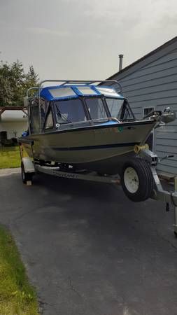 A Hewescraft Sea Runner 210 boat on a trailer next to a building.