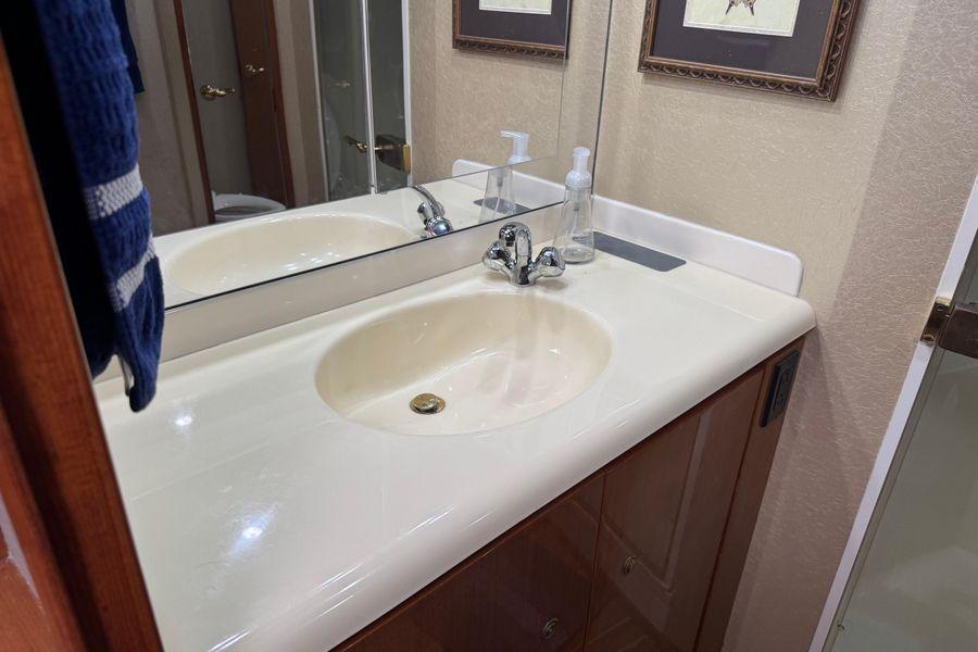 Bathroom sink area in 2002 Viking 61 Enclosed Bridge yacht, featuring mirror and faucet.