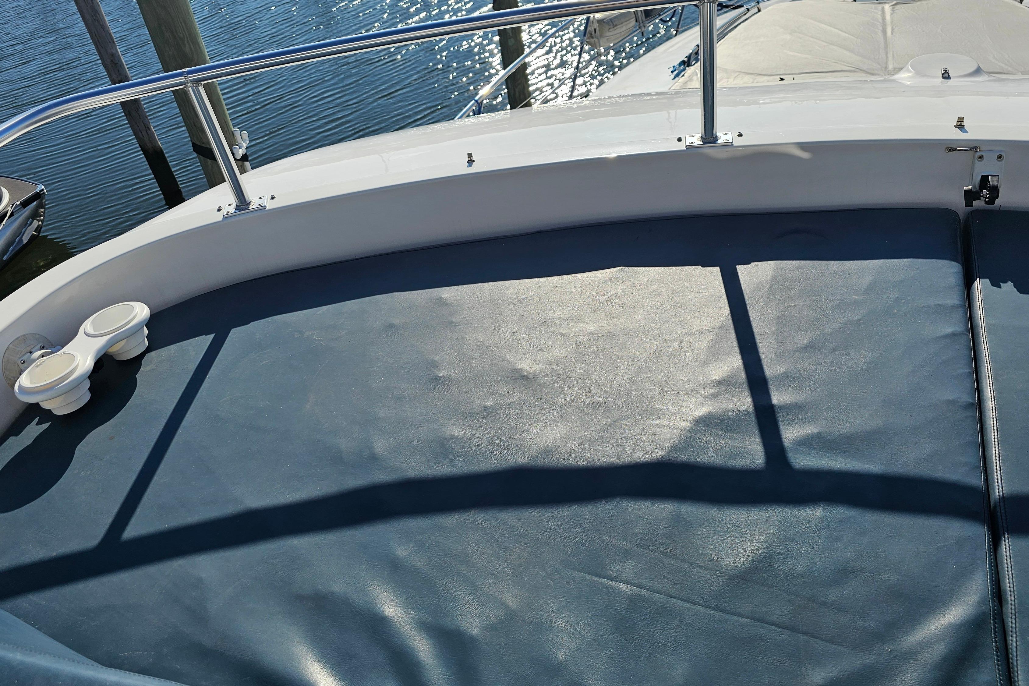 2005 Neptunus 56 Flybridge yacht with cushioned seating and railing, docked by the water.