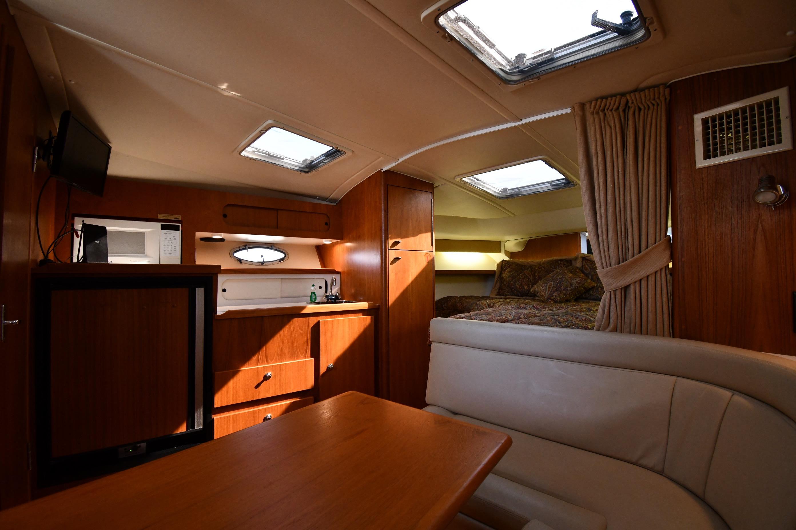 Interior of 1998 Tiara Yachts 3100 Open, featuring cozy cabin with kitchenette and seating area.