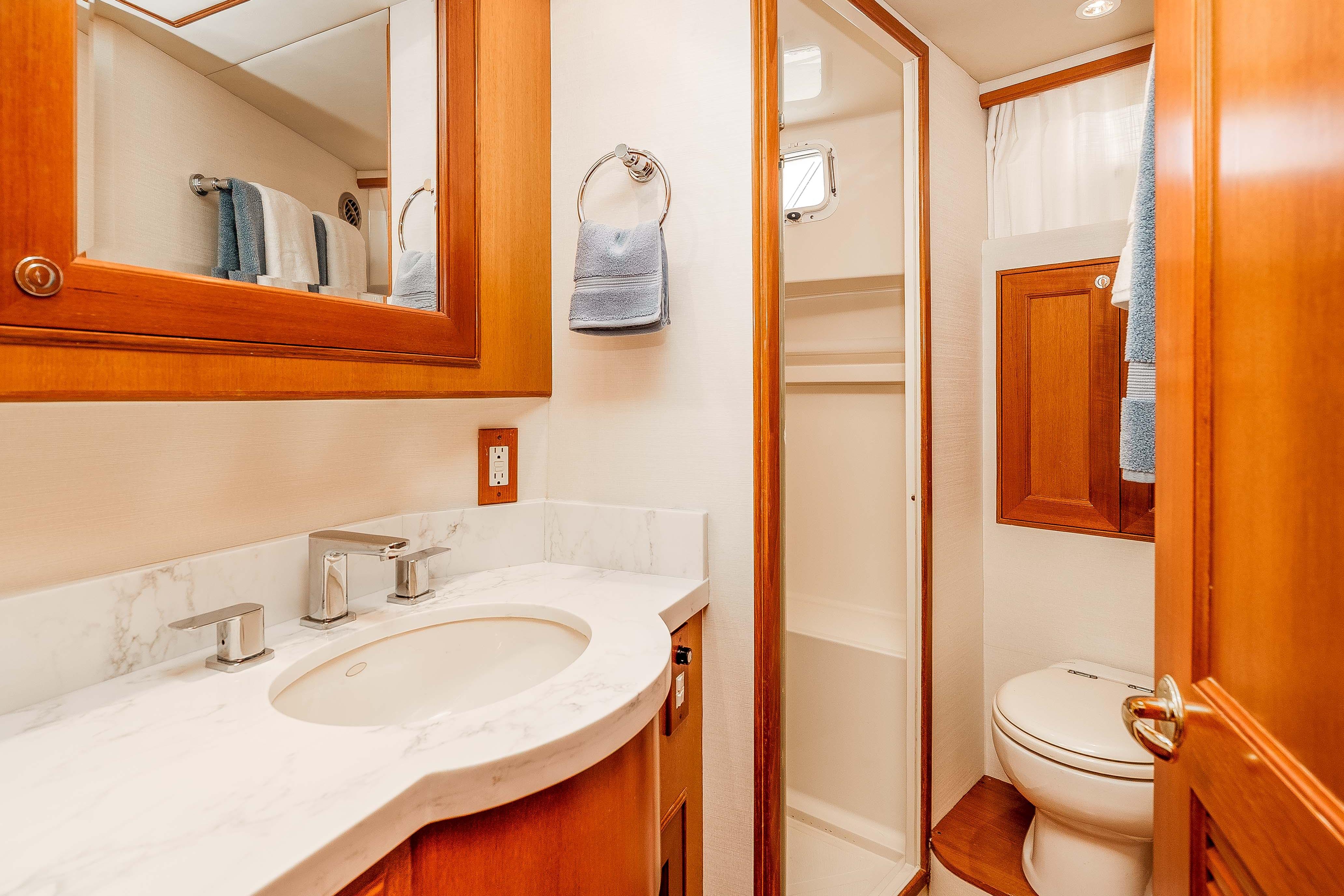 Luxurious bathroom in 2005 Offshore Yachts 54 Pilothouse, featuring elegant wood cabinetry and modern fixtures.