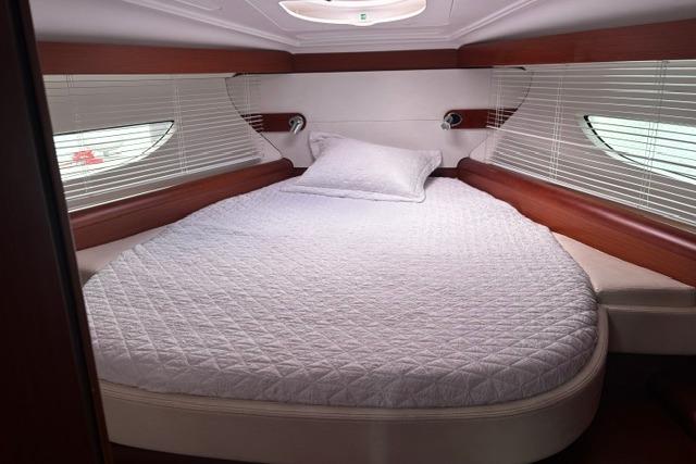 2013 Beneteau Gran Turismo 38 cabin with cozy bed and elegant wood accents.