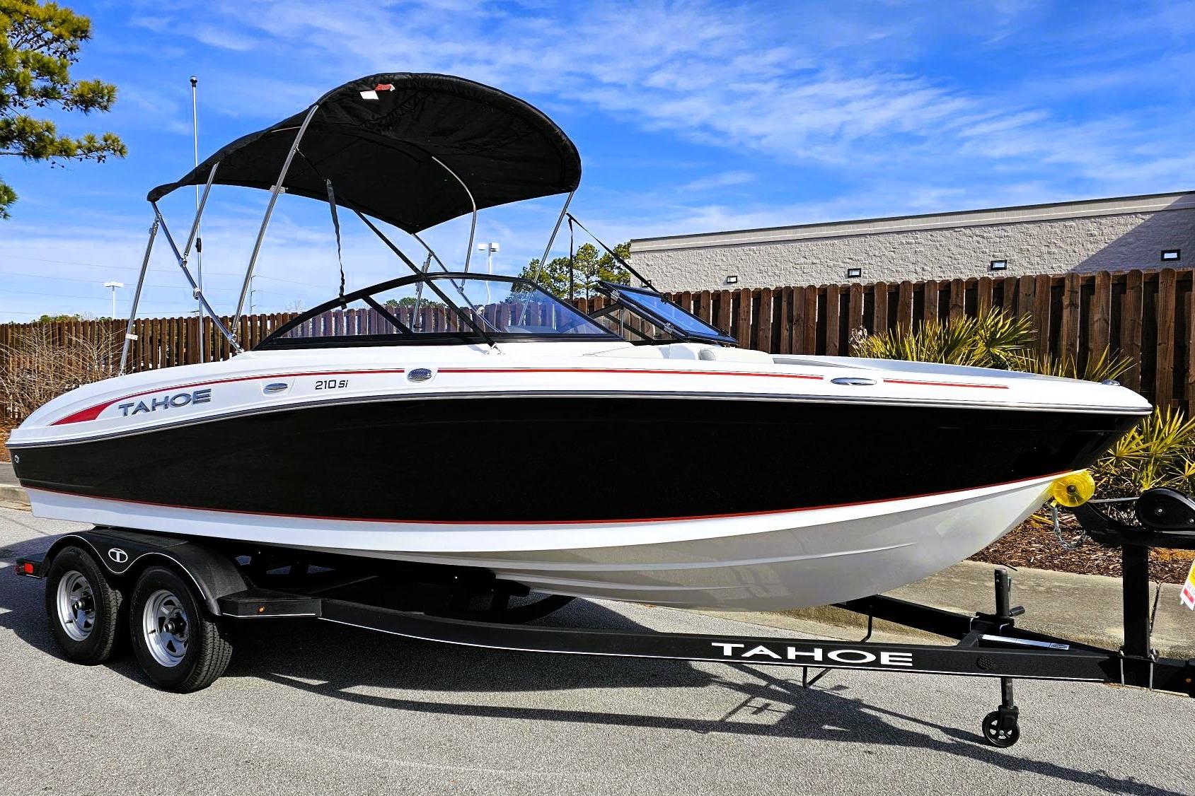 2023 Tahoe 210 Si boat on trailer, black and white design, parked outdoors.
