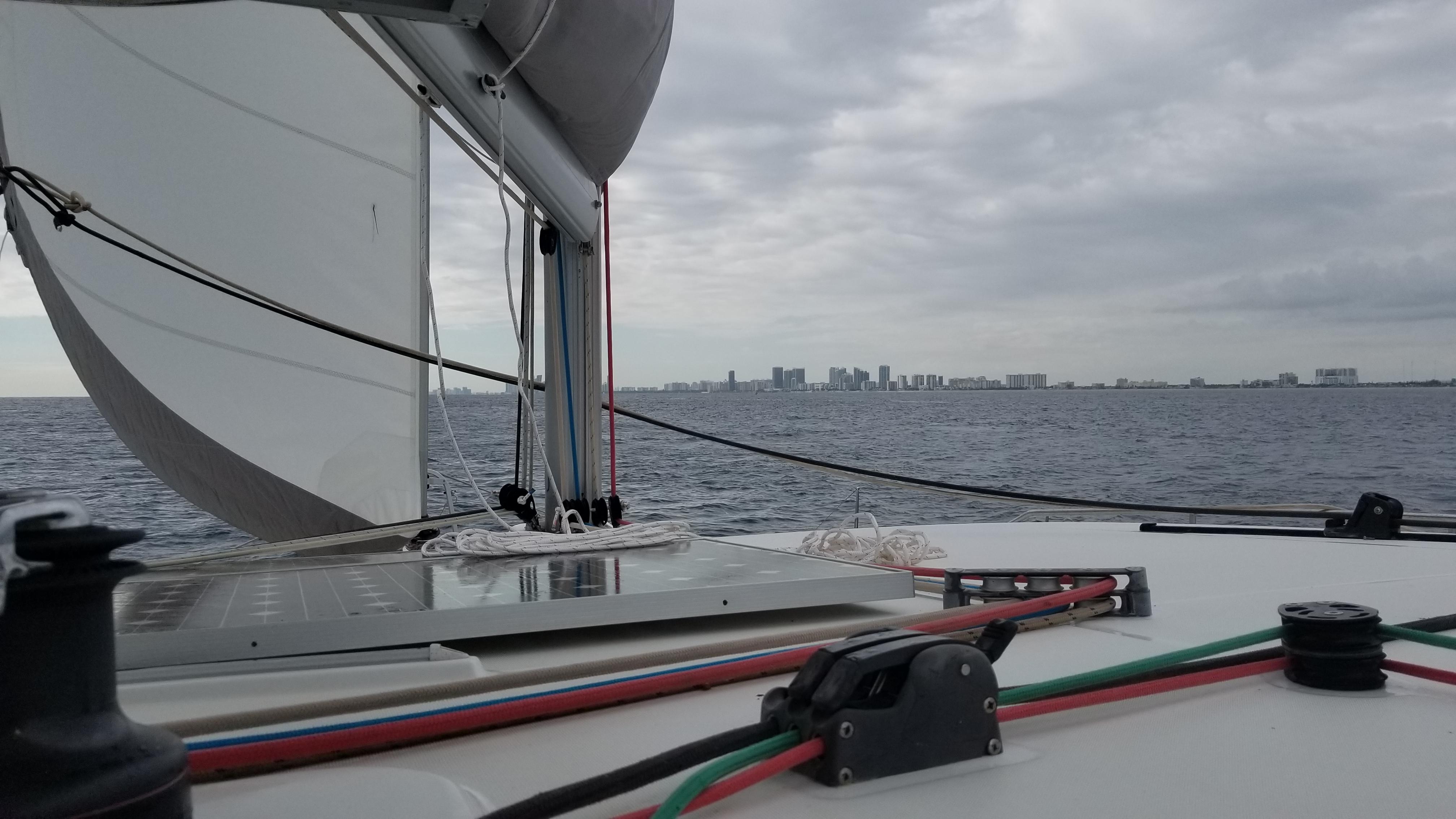 Sailing on a 2010 Lagoon 400 catamaran with city skyline in the distance.