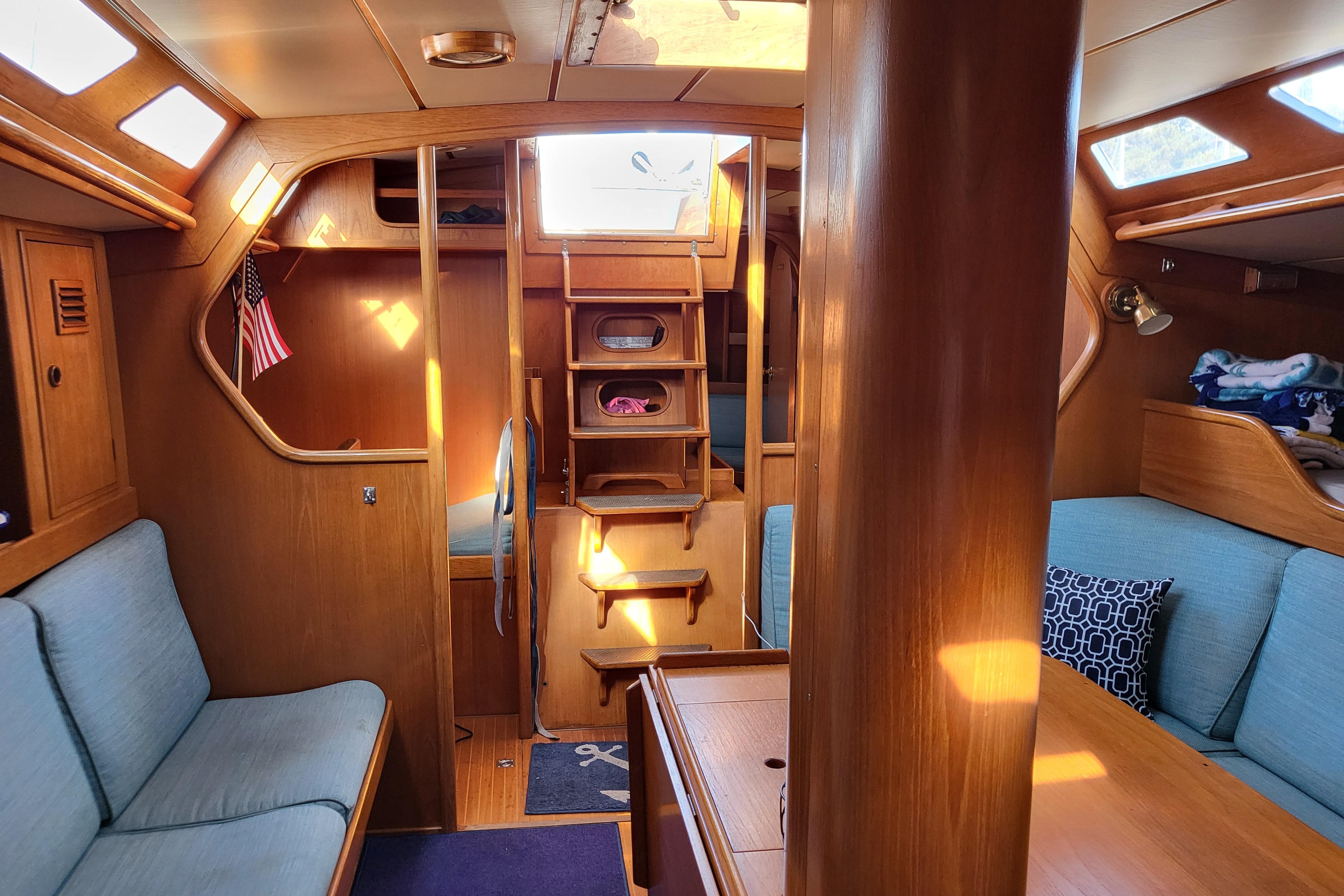 Interior of a 1985 Swan 46 yacht with wooden furnishings and cozy seating.