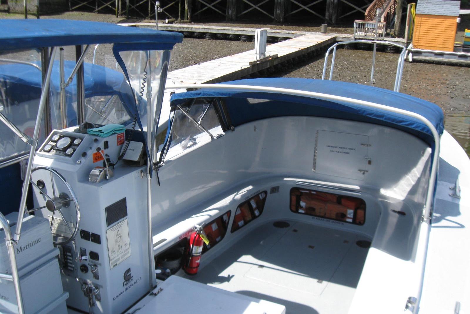 1994 Willard US Navy boat with blue canopy and control panel docked at a marina.