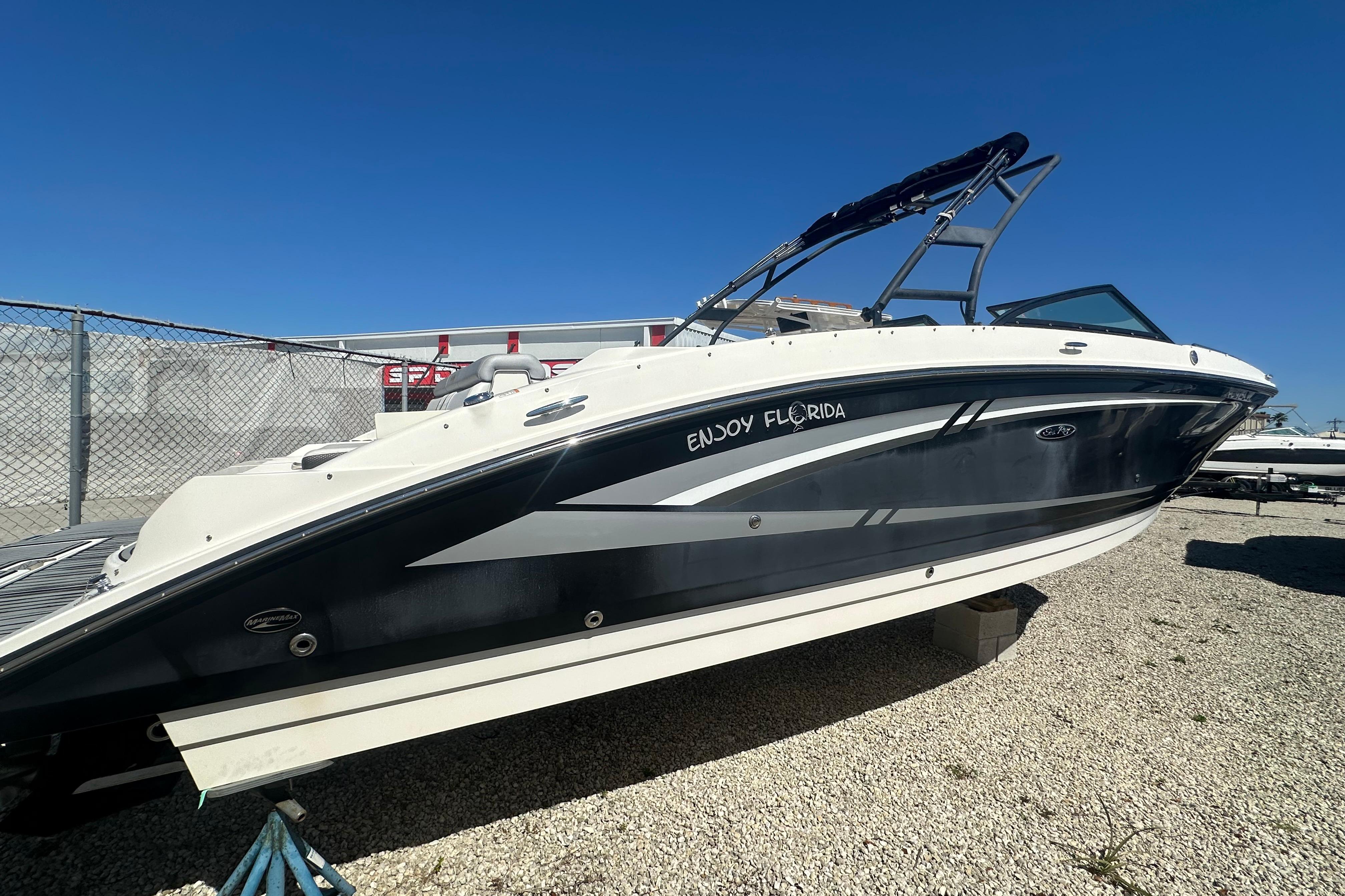 2016 Sea Ray 270 Sundeck boat on gravel lot under clear blue sky.