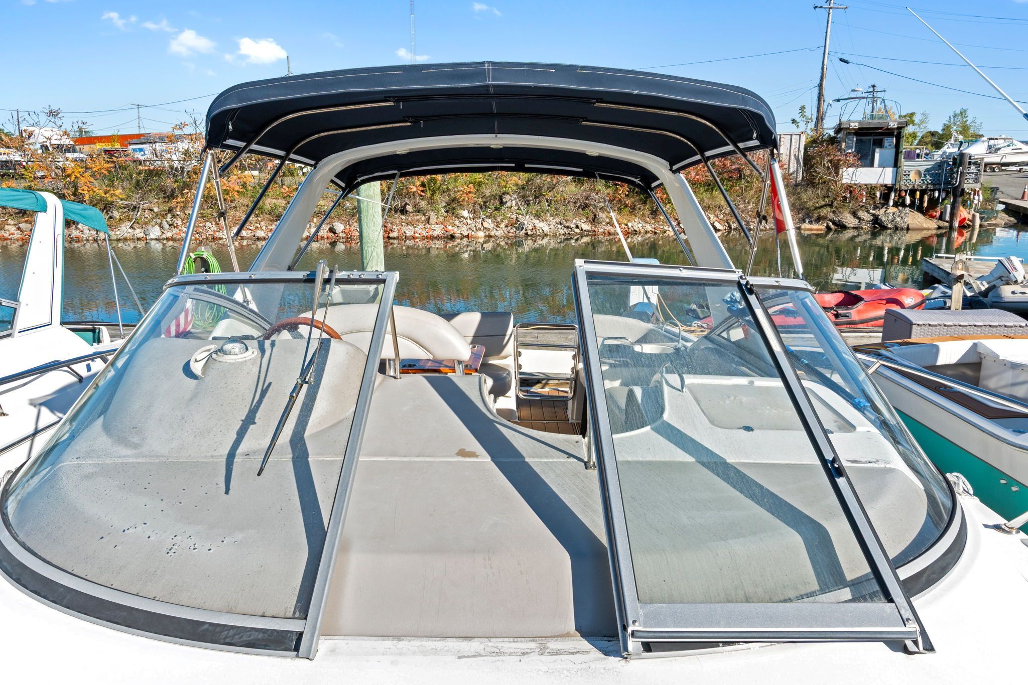 A 2007 Larson Cabrio 330 with open cockpit and canopy, docked in a harbor.