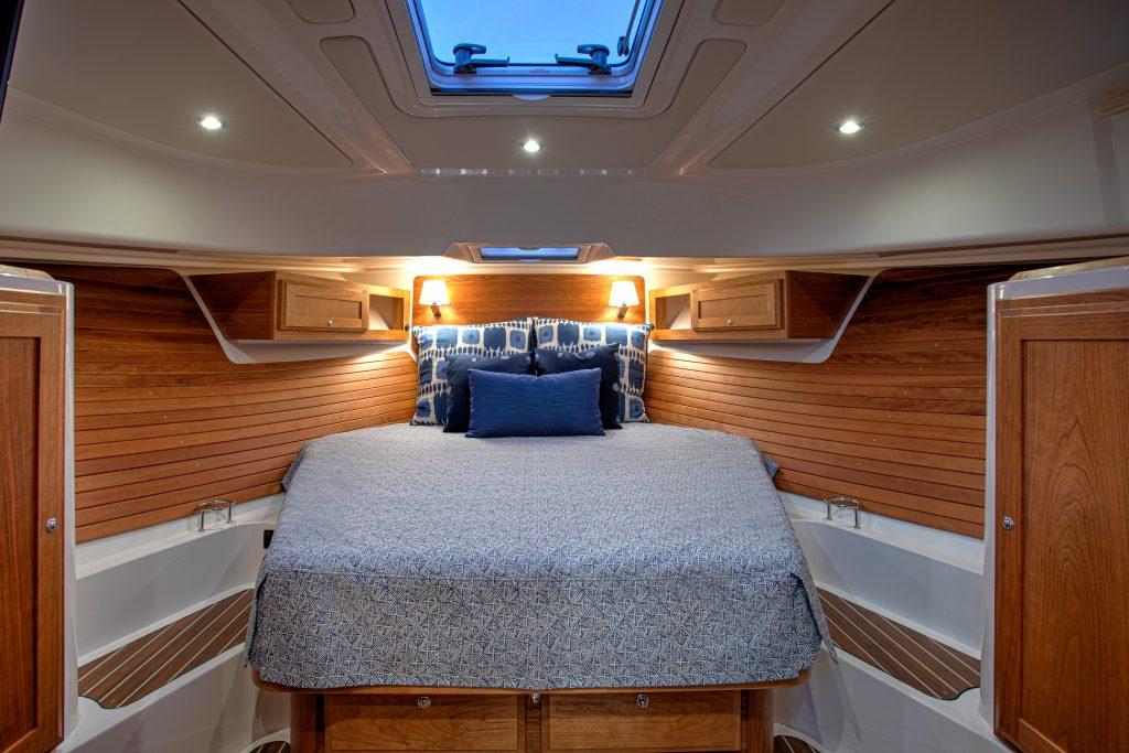 Luxurious cabin interior of 2026 Back Cove 39O yacht with cozy bedding and wooden accents.