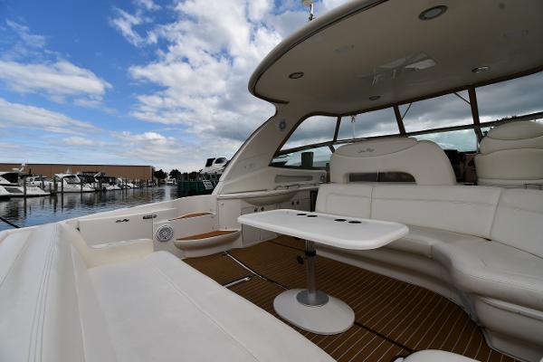 2003 Sea Ray 460 Sundancer yacht with spacious seating and table, docked under a blue sky.