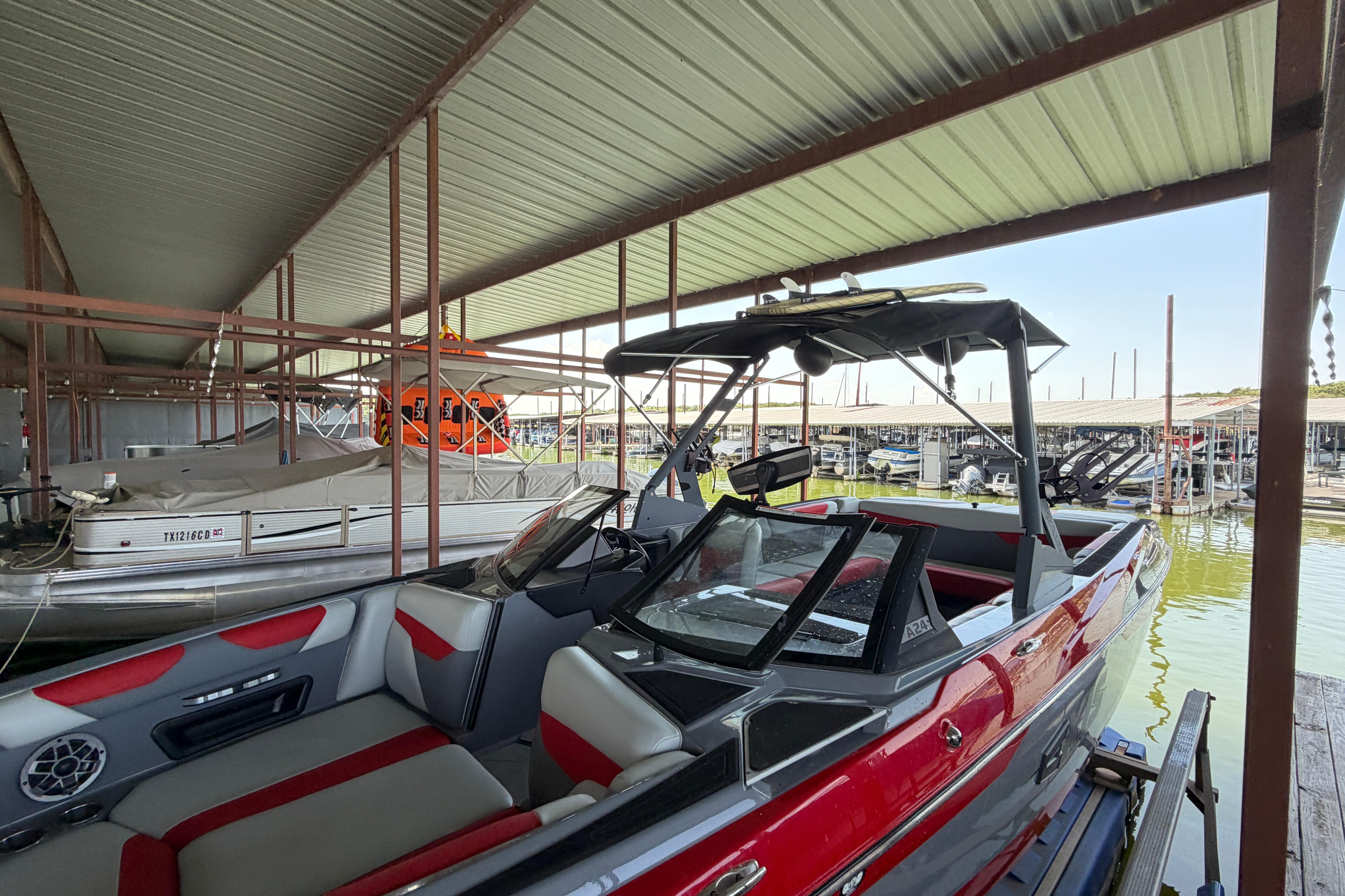 2021 Axis A24 boat docked in a marina, featuring red and gray interior.