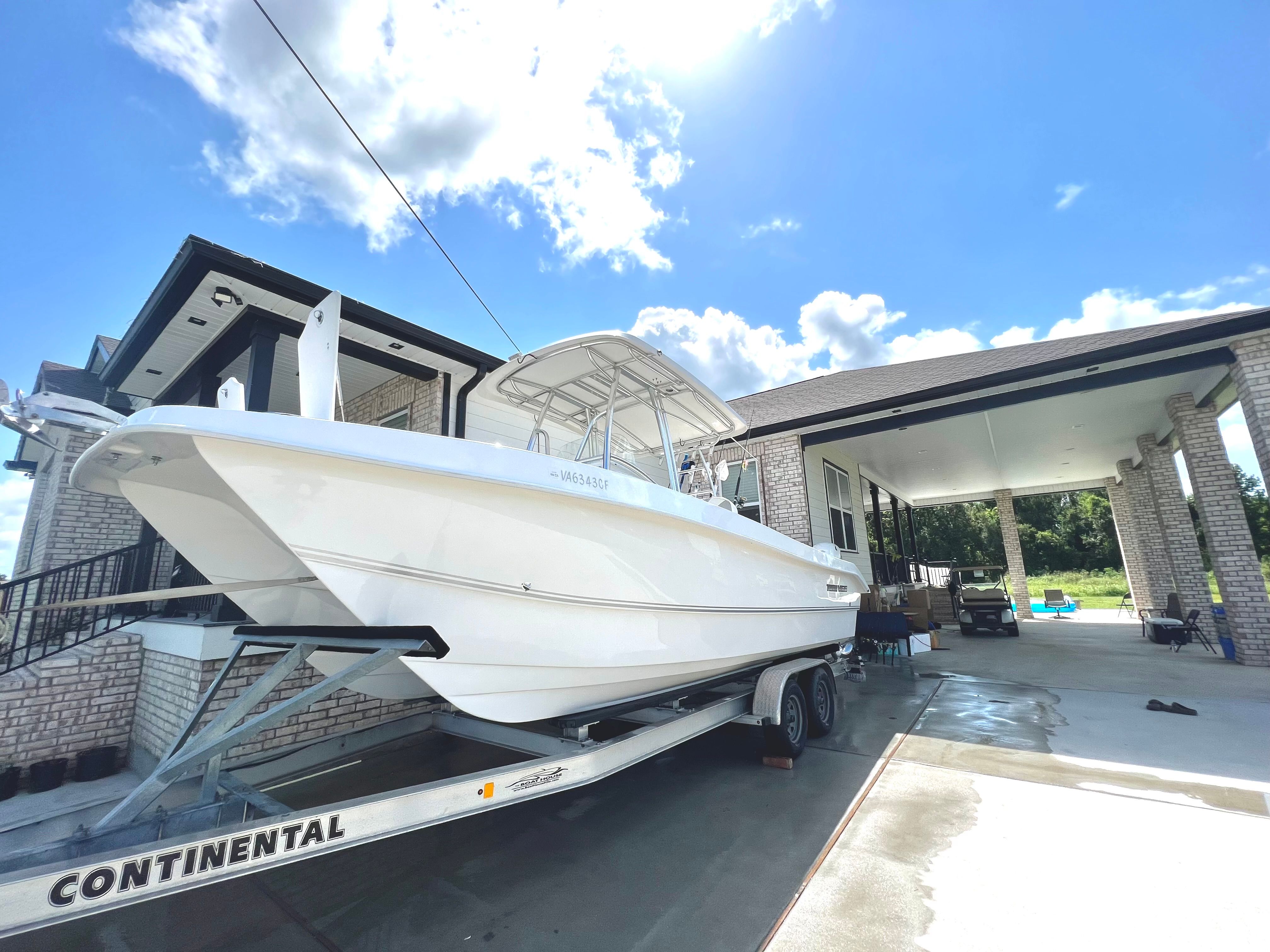 A Twin Vee Ocean Cat boat on a trailer in front of a modern house.