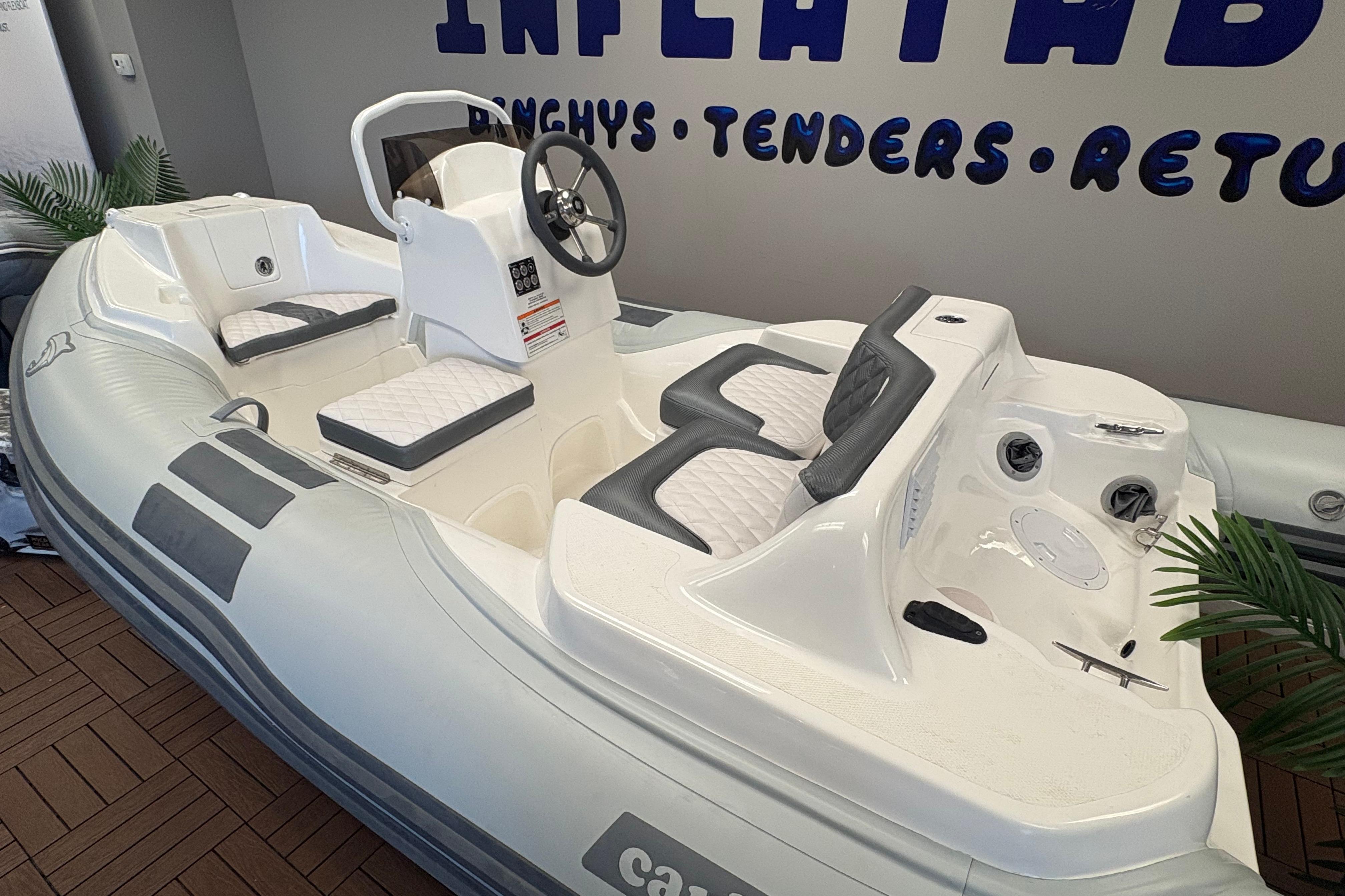 Inflatable Caribe DL12 boat, 2026 model, with white and gray seating, displayed indoors.