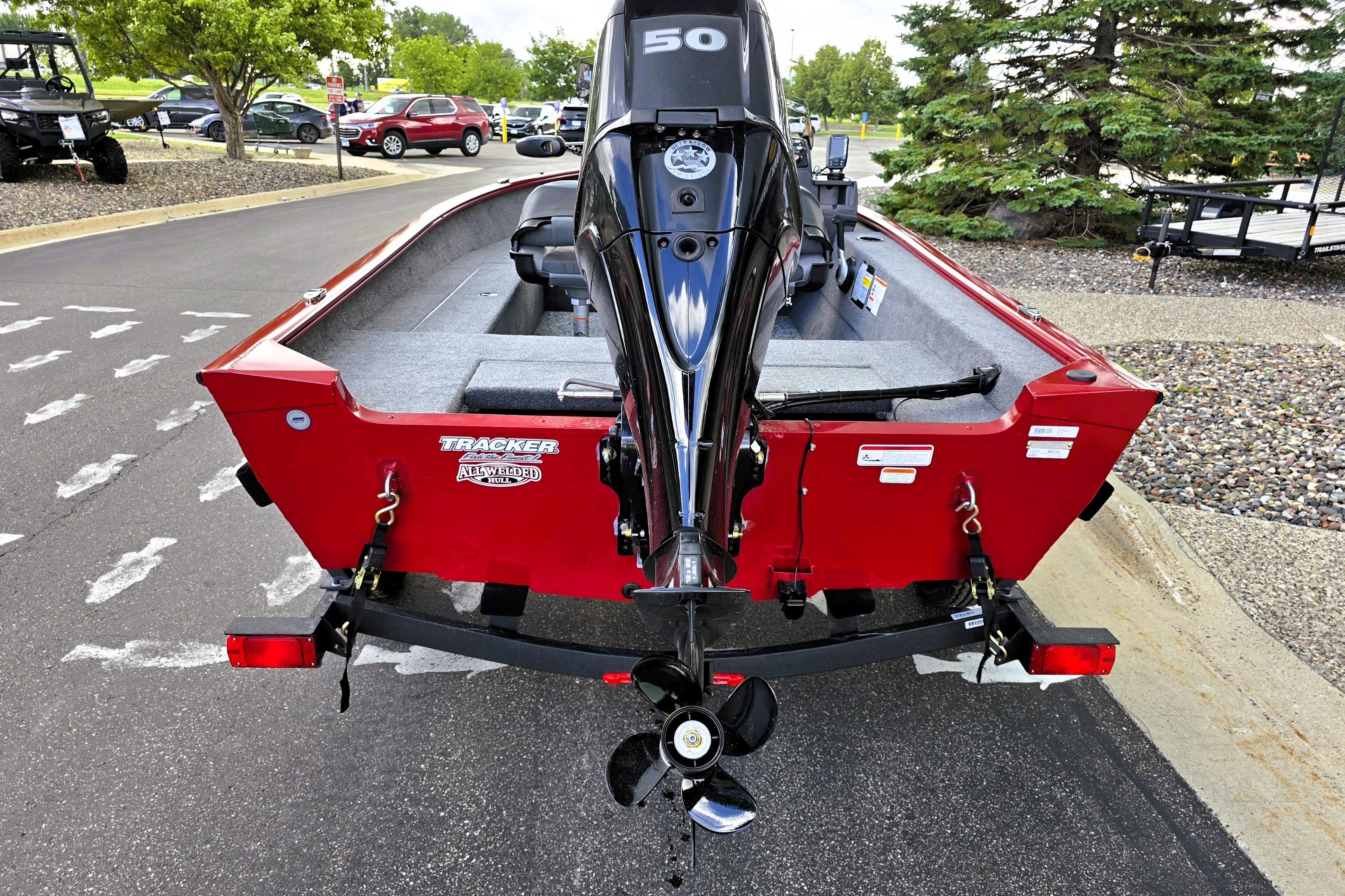 Red 2026 Tracker Super Guide V-16 SC boat with outboard motor, parked outdoors.