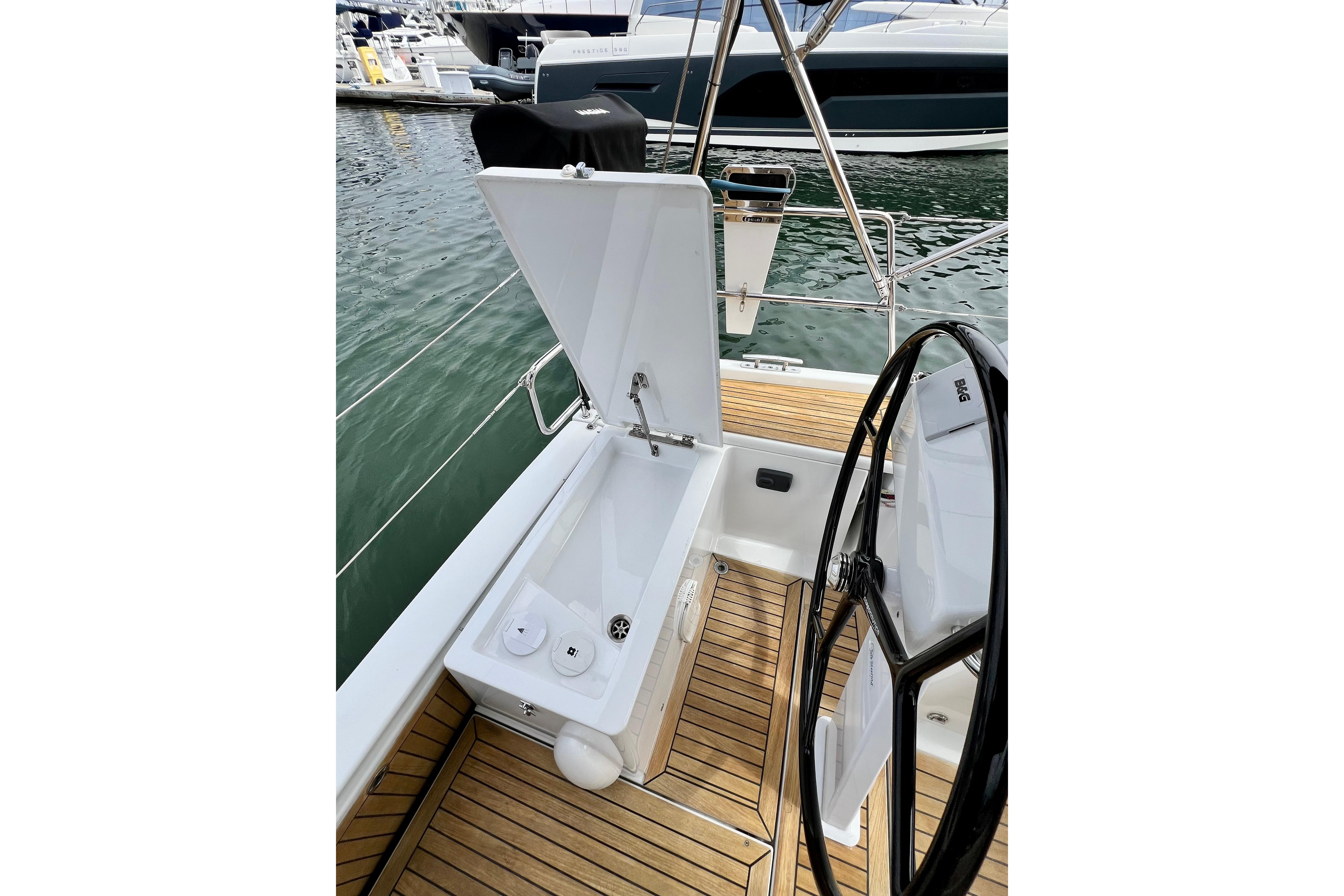 Cockpit of 2016 Hanse 455 yacht with open storage compartment and steering wheel.