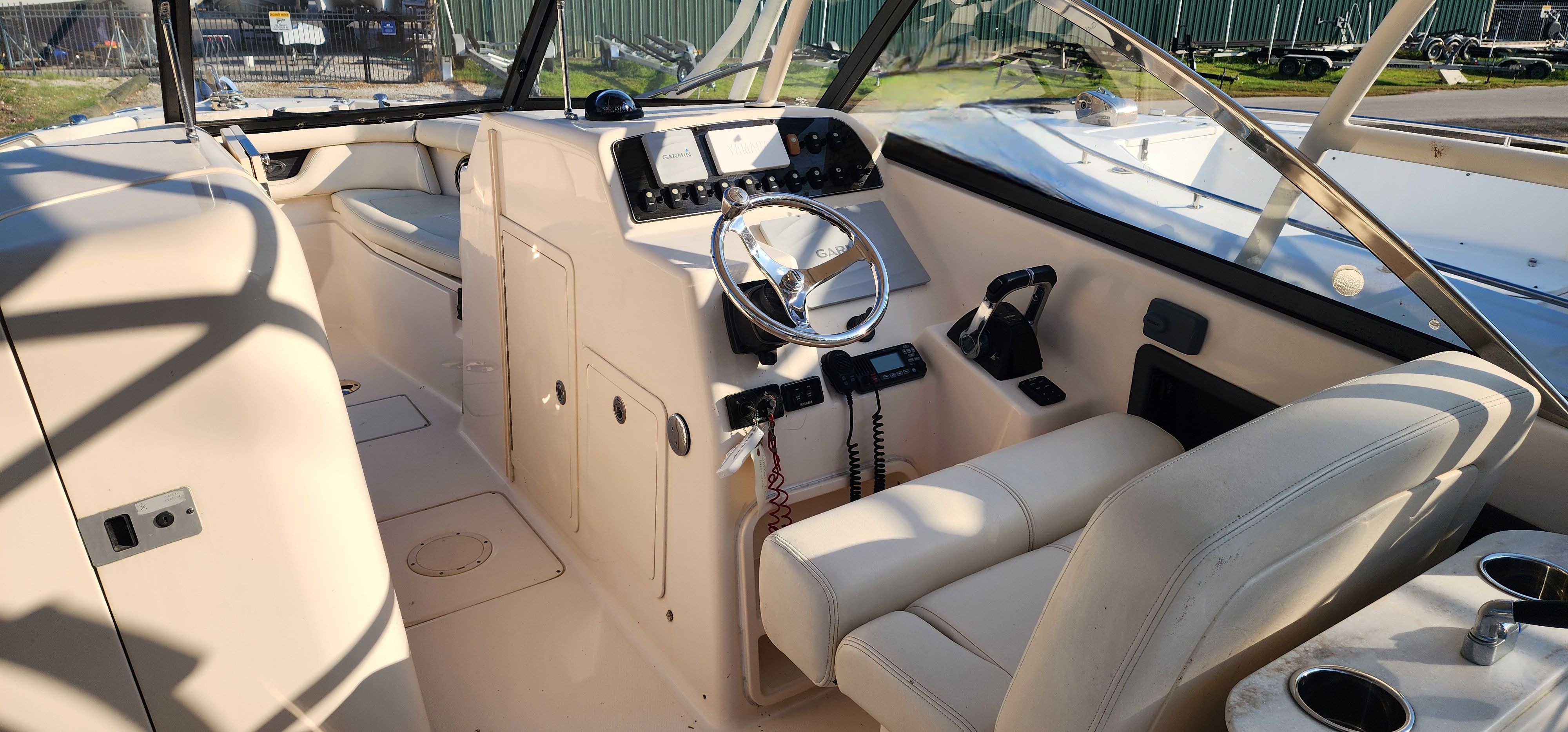 The image shows the cockpit of a 2015 Grady-White Freedom 275 with beige seats and a helm console.