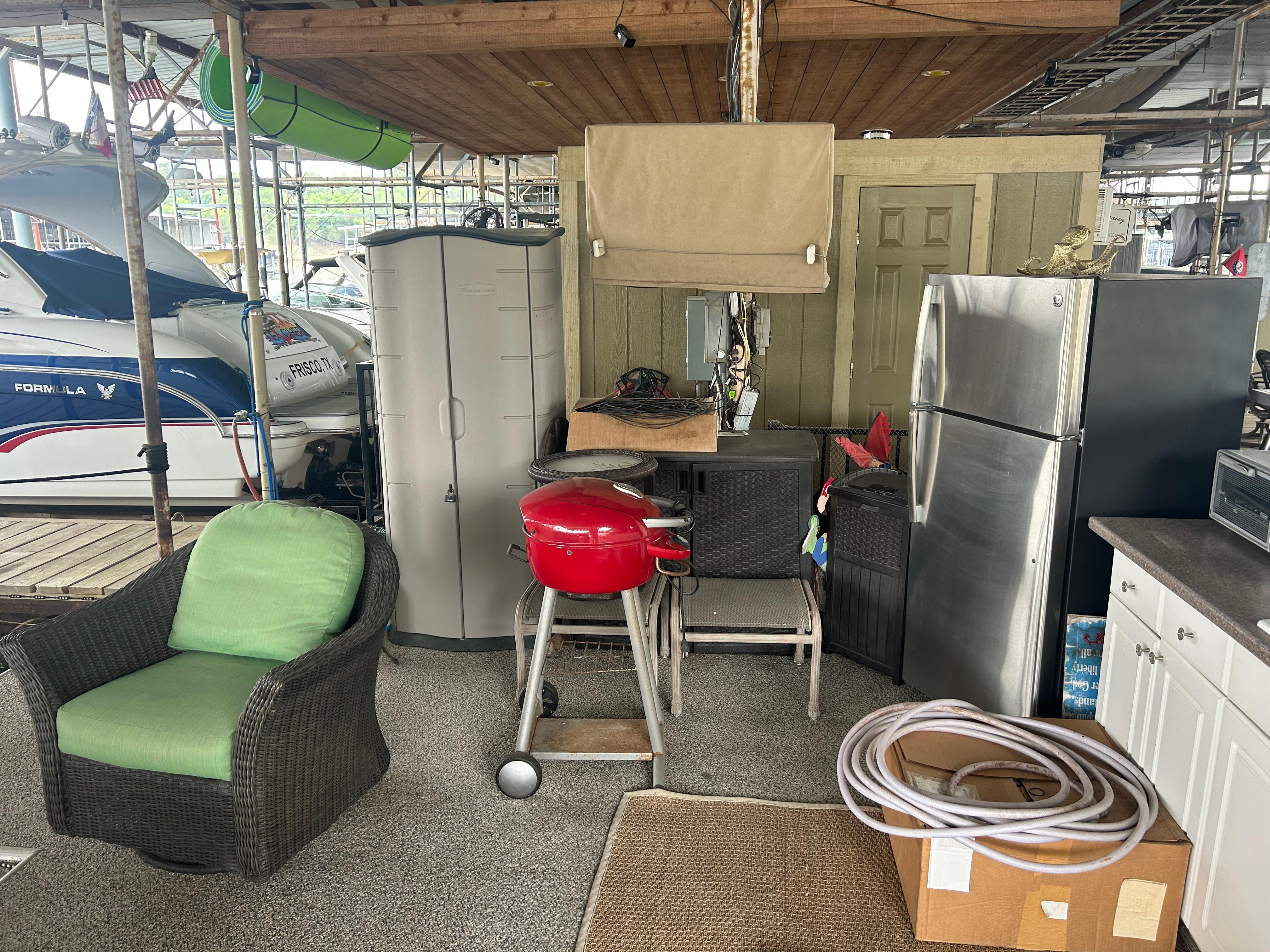 Cozy dock setup with grill, chairs, and storage near 1996 Carver 440 Aft Cabin Motor Yacht.