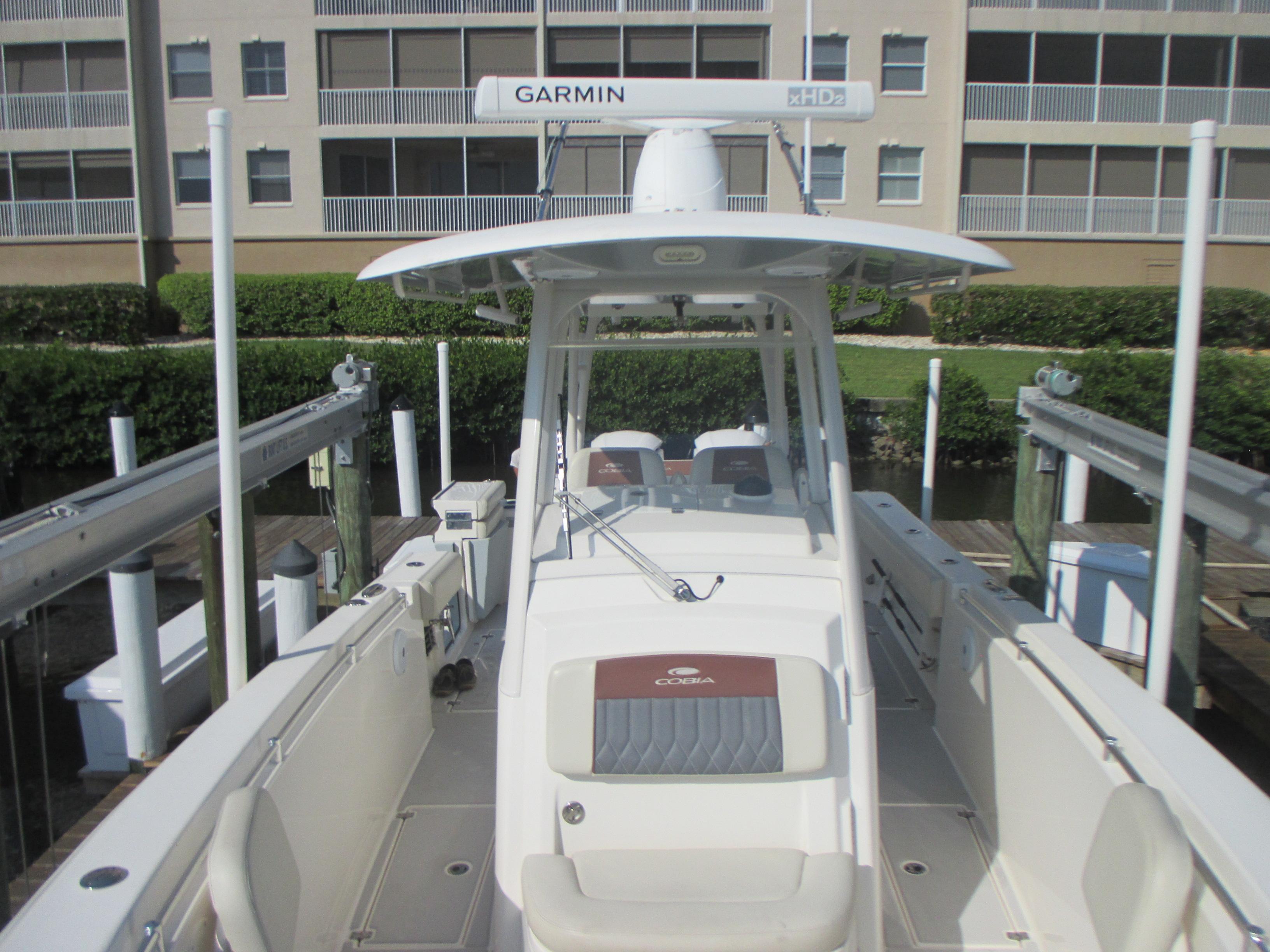 2018 Cobia 301 Center Console boat docked, featuring Garmin radar and spacious seating.