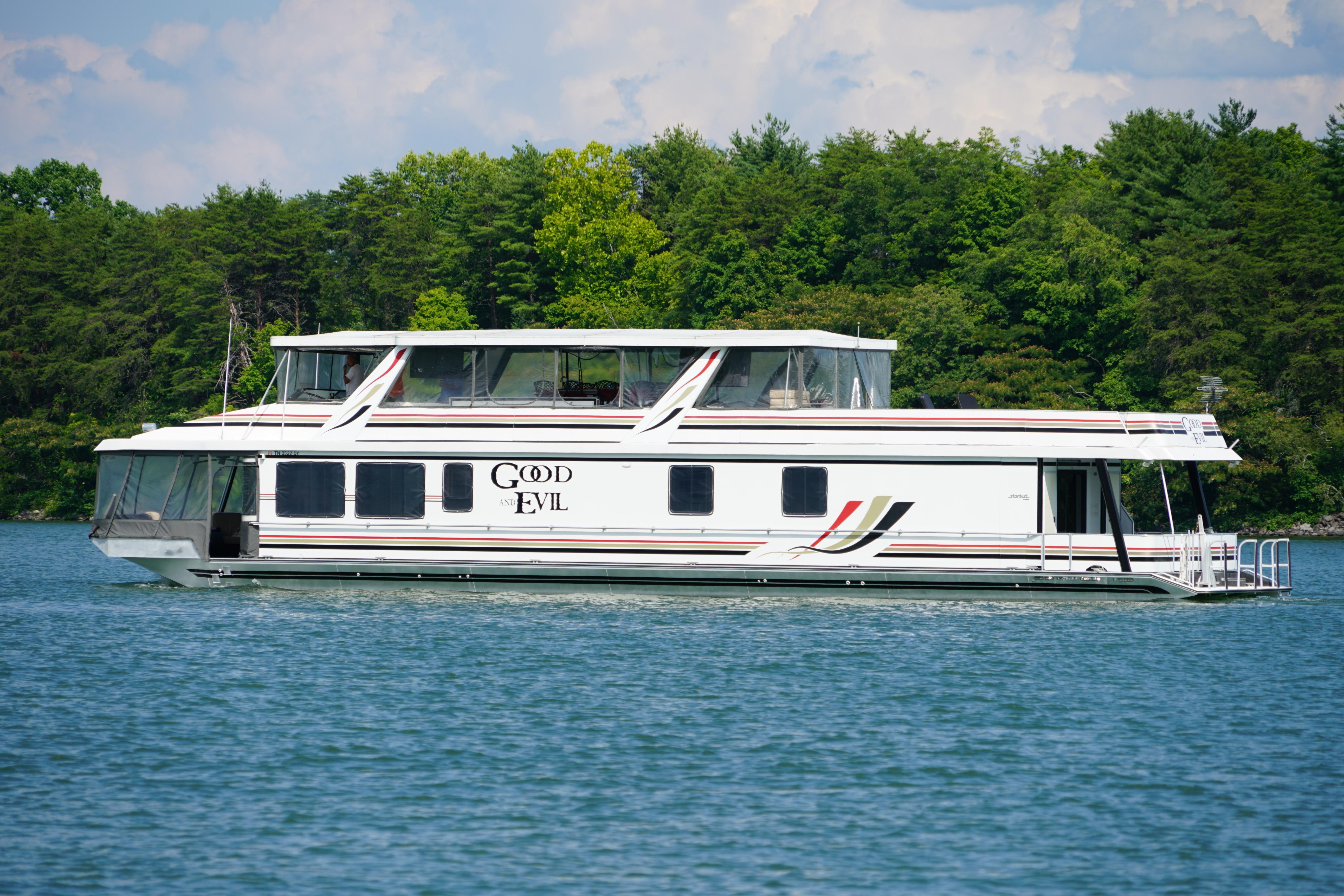 Houseboat on a lake, Stardust Cruisers 83'x17', year 2000, with forested background.