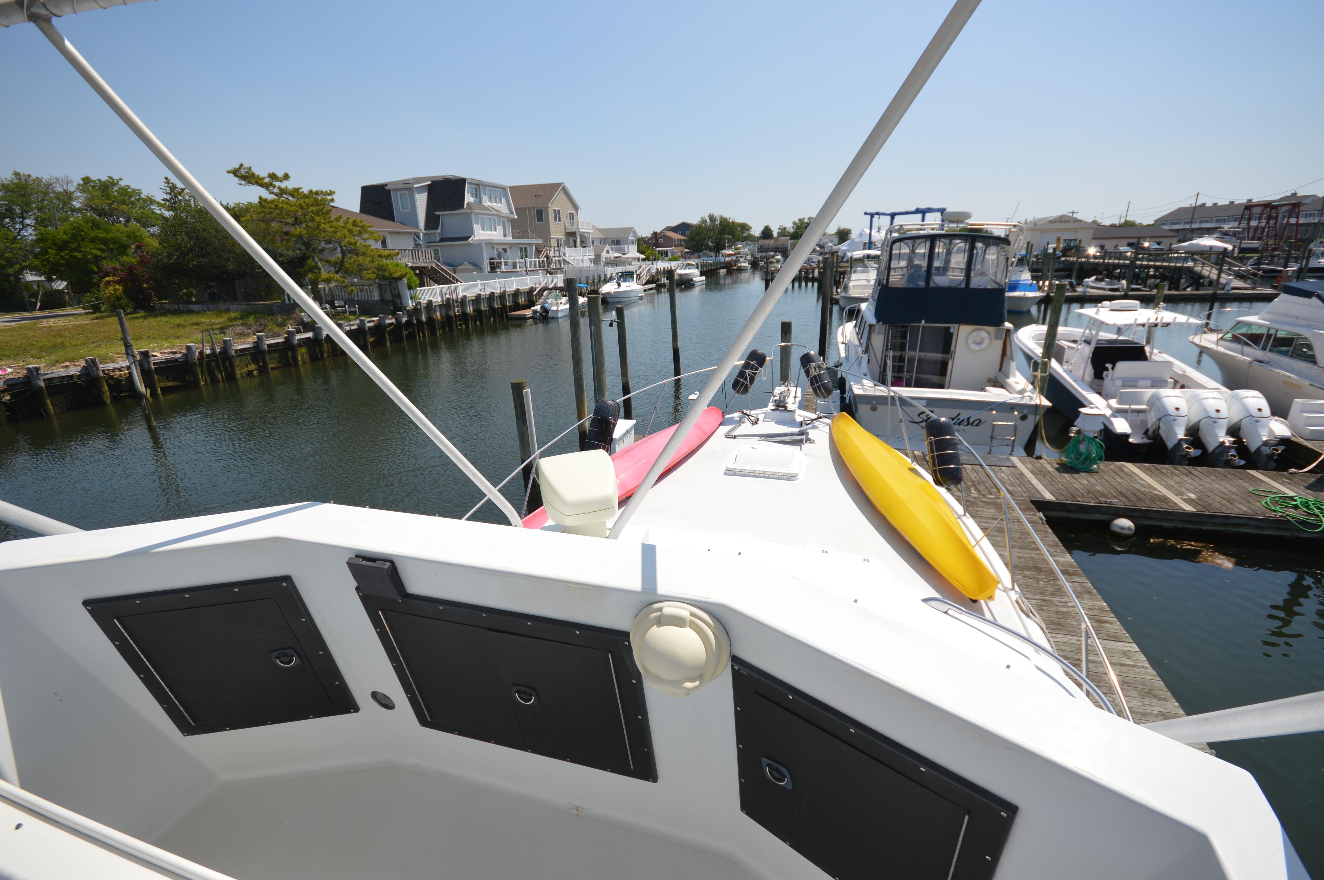 1973 Hatteras 45 Convertible docked in a marina with kayaks on deck.