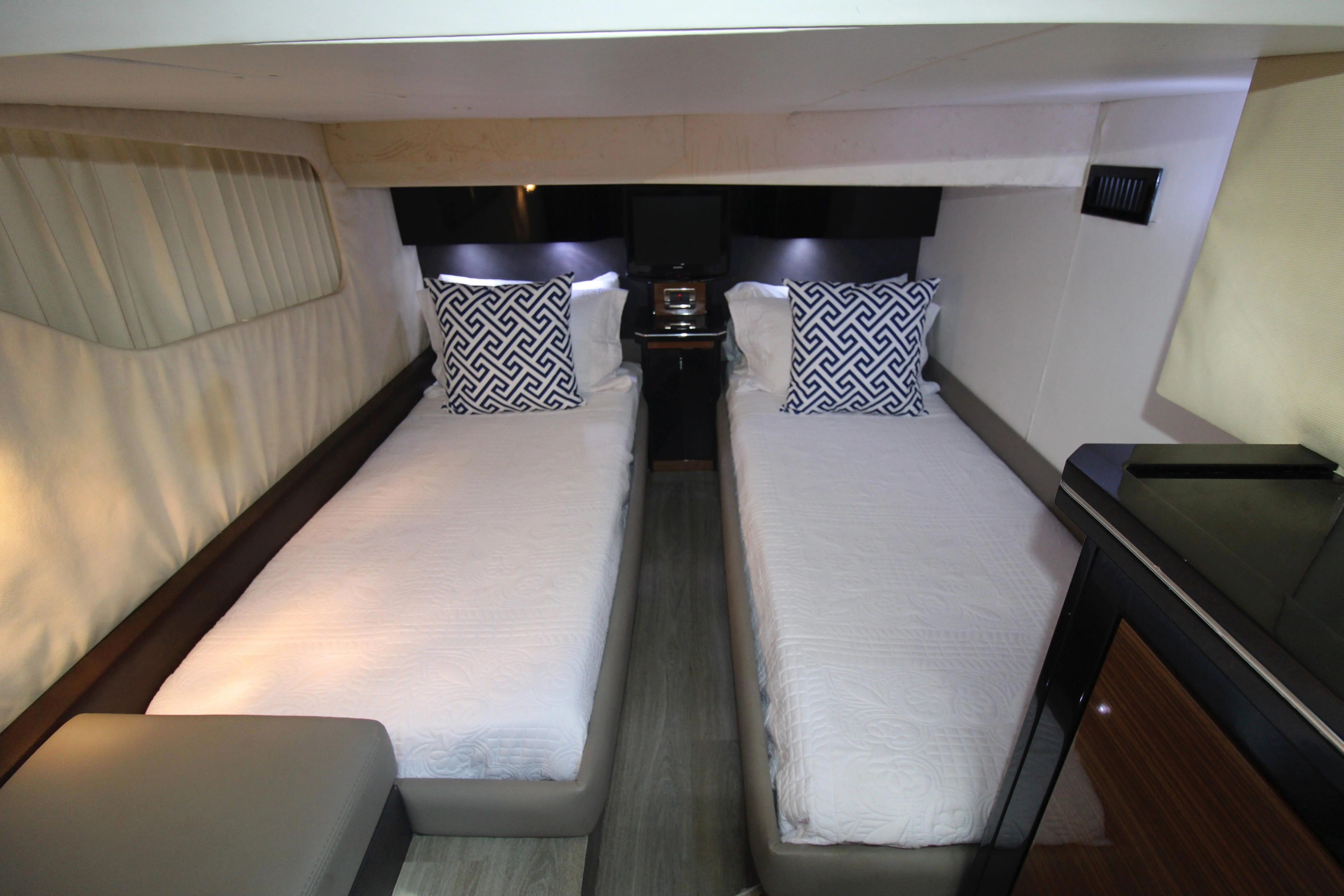 Two single beds in a sleek cabin with modern pillows and soft lighting.