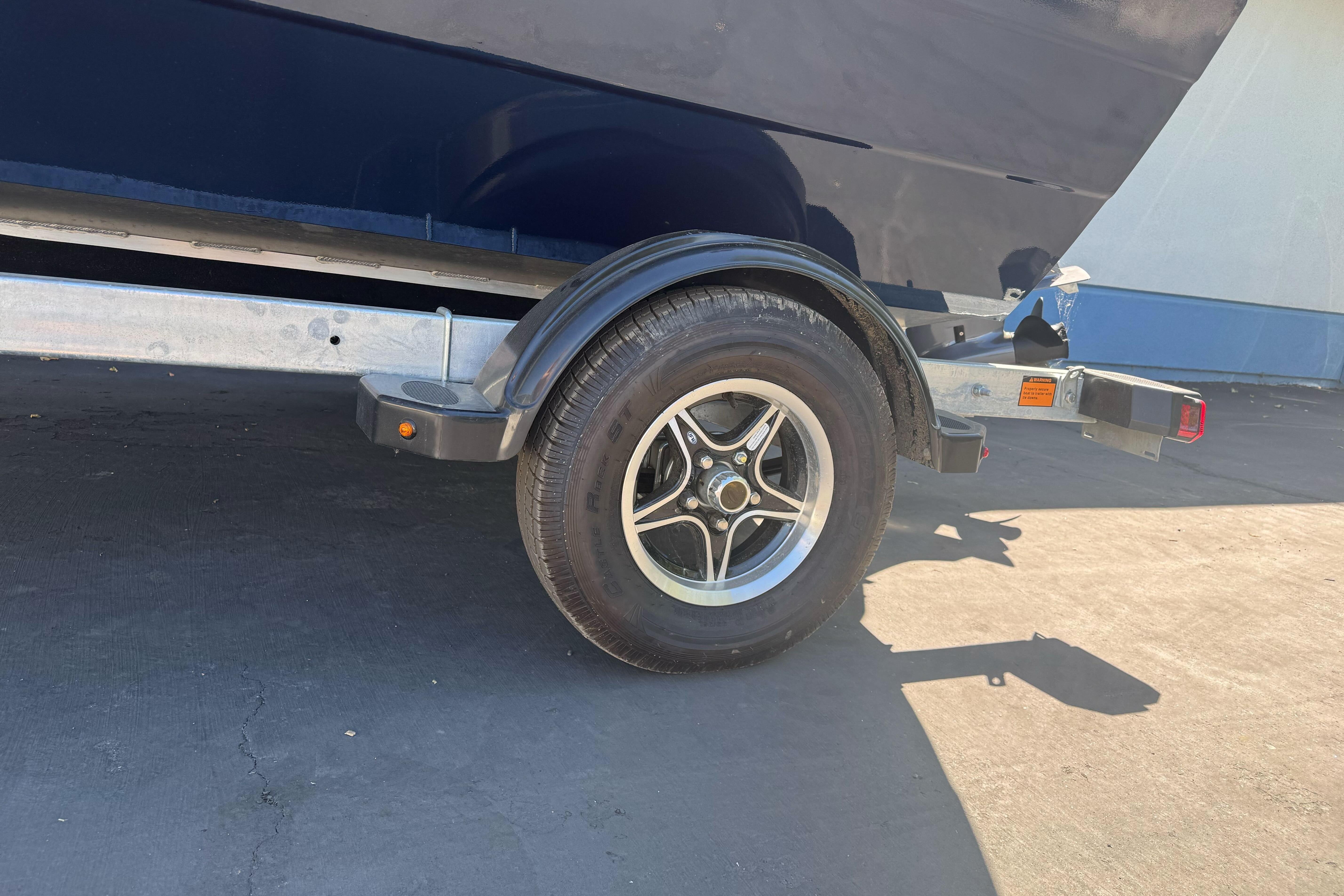 Trailer wheel of 2026 KingFisher 16 Falcon boat on pavement.