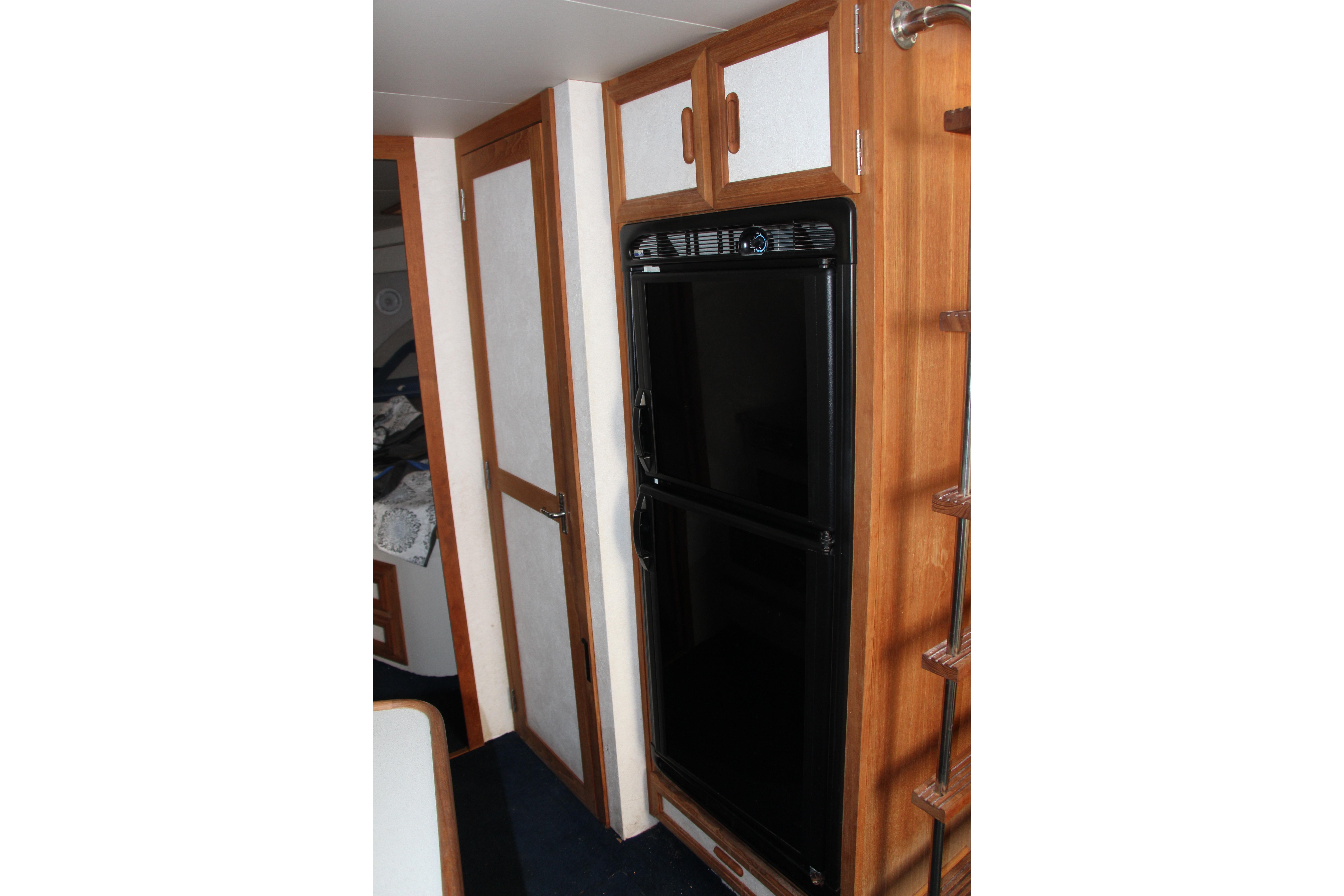 Interior of 1995 Carver 330 Mariner with black fridge and wooden cabinetry.