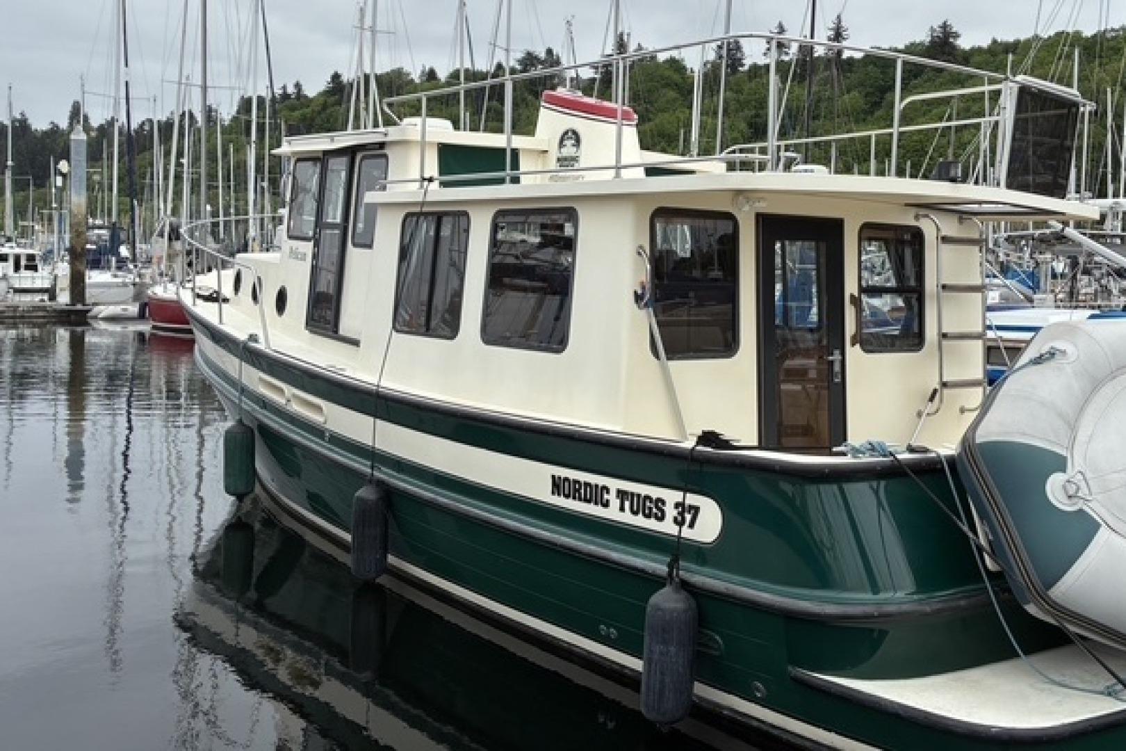 2000 Nordic Tug 37 docked in a marina, showcasing its classic design and sturdy build.
