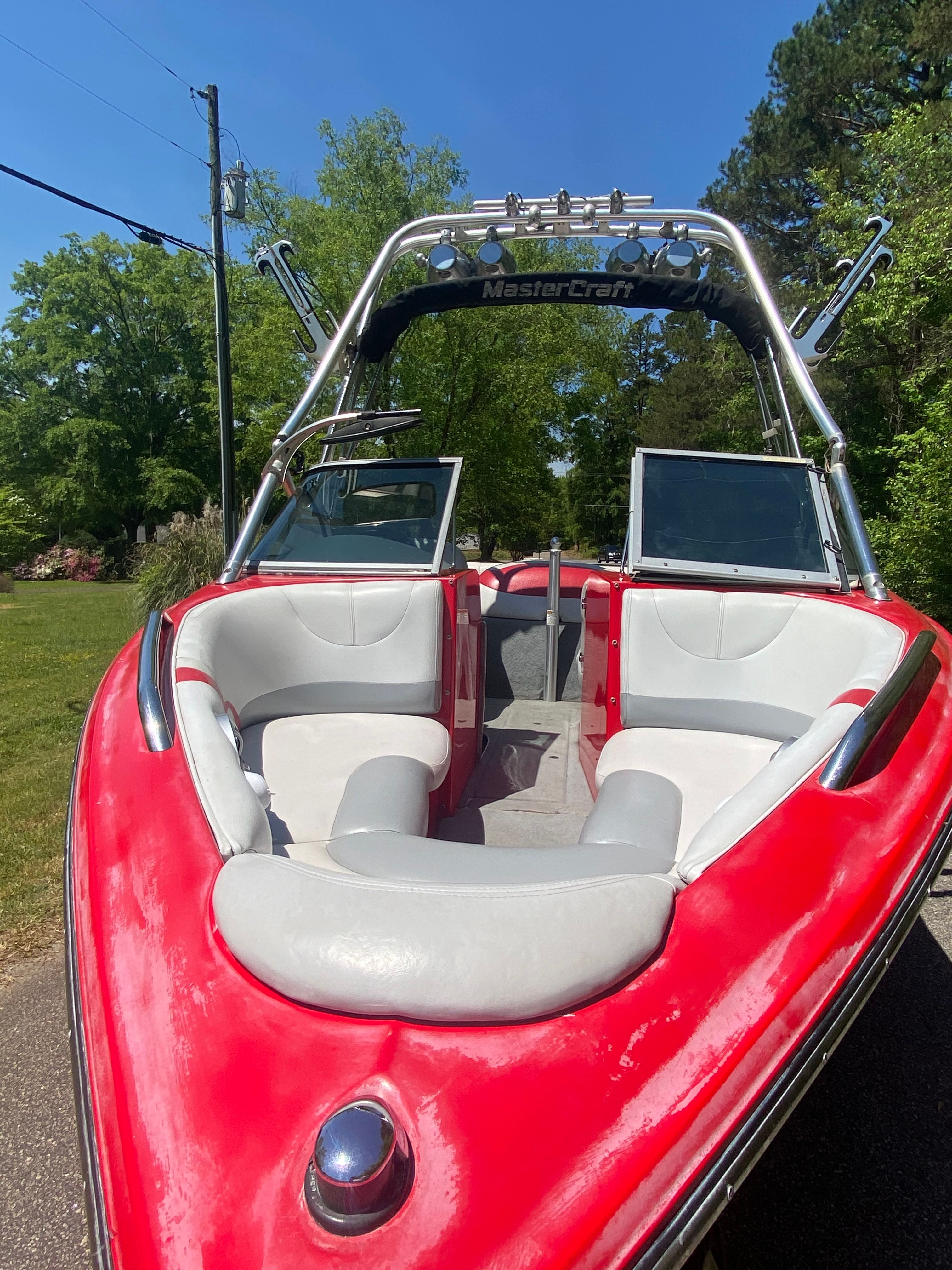 A red 2004 MasterCraft X-9 boat with gray seats, parked on a road.