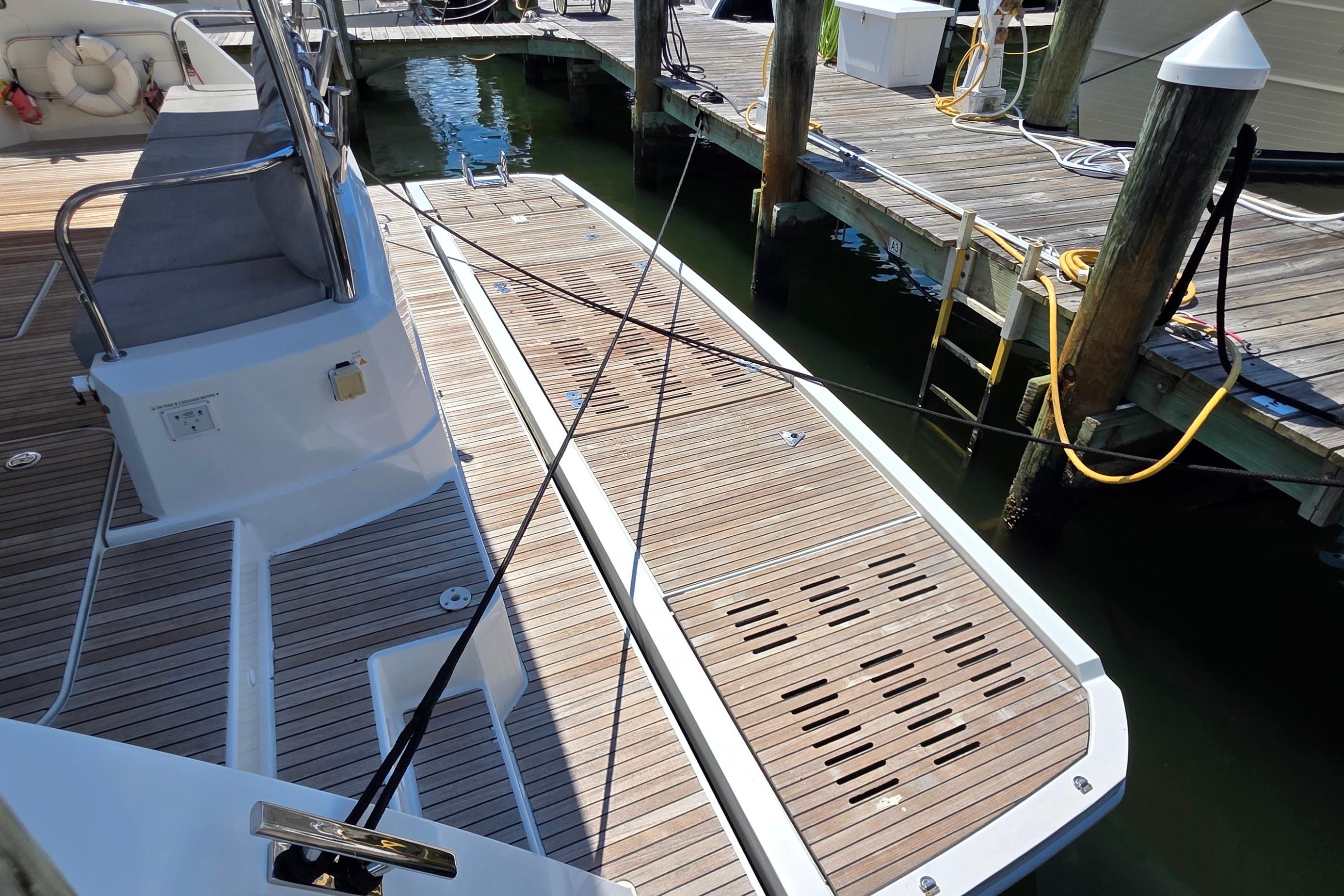 Fountaine Pajot Motor Yacht 44, 2018 model, docked with wooden deck and seating area.