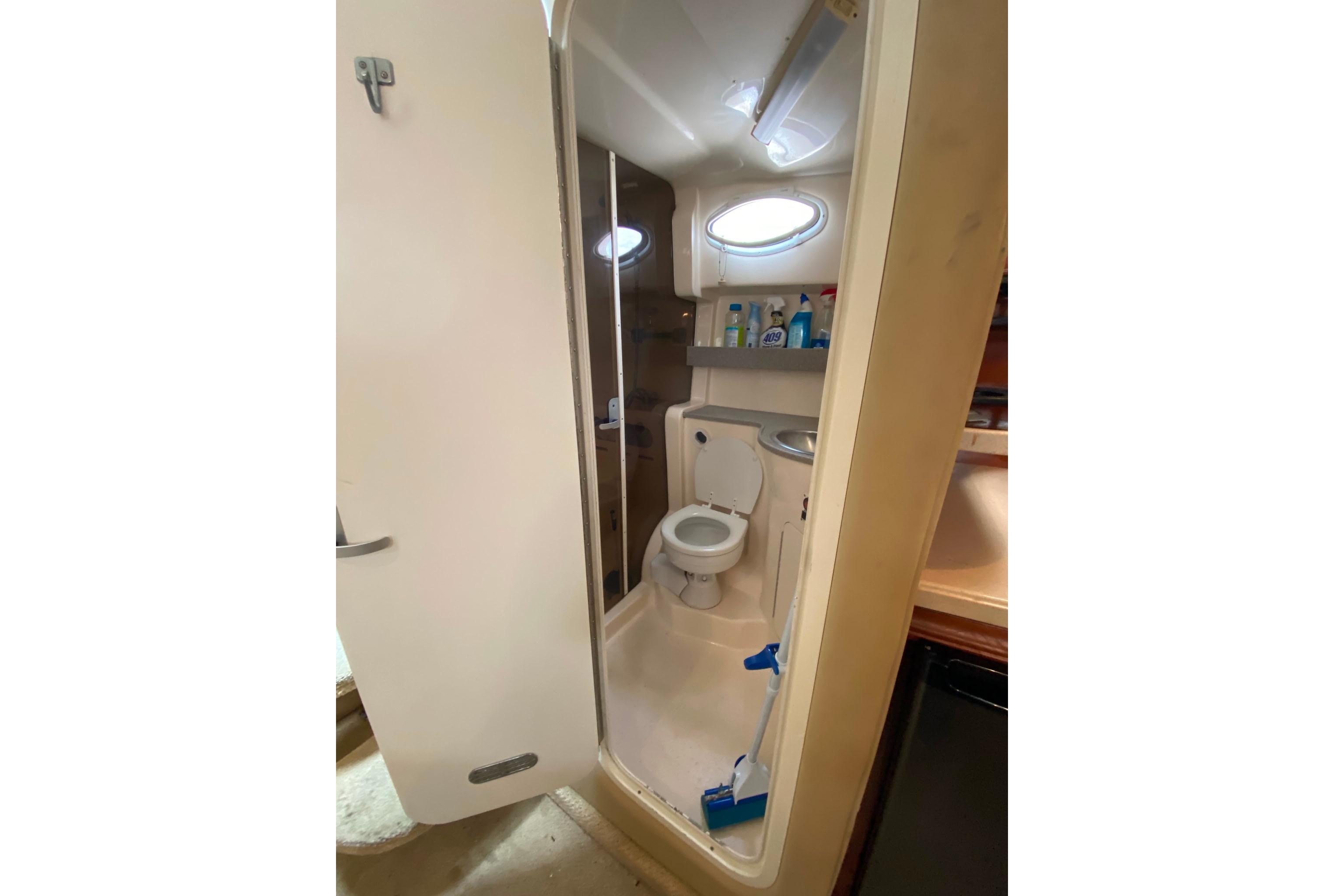 2003 Rinker Fiesta Vee 342 boat bathroom with toilet, sink, and cleaning supplies.
