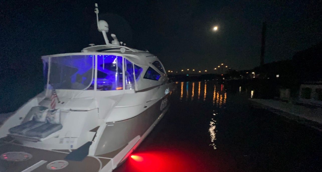 A 2009 Cruisers Yachts 520 Sports Coupe on the water at night, illuminated by red lights.
