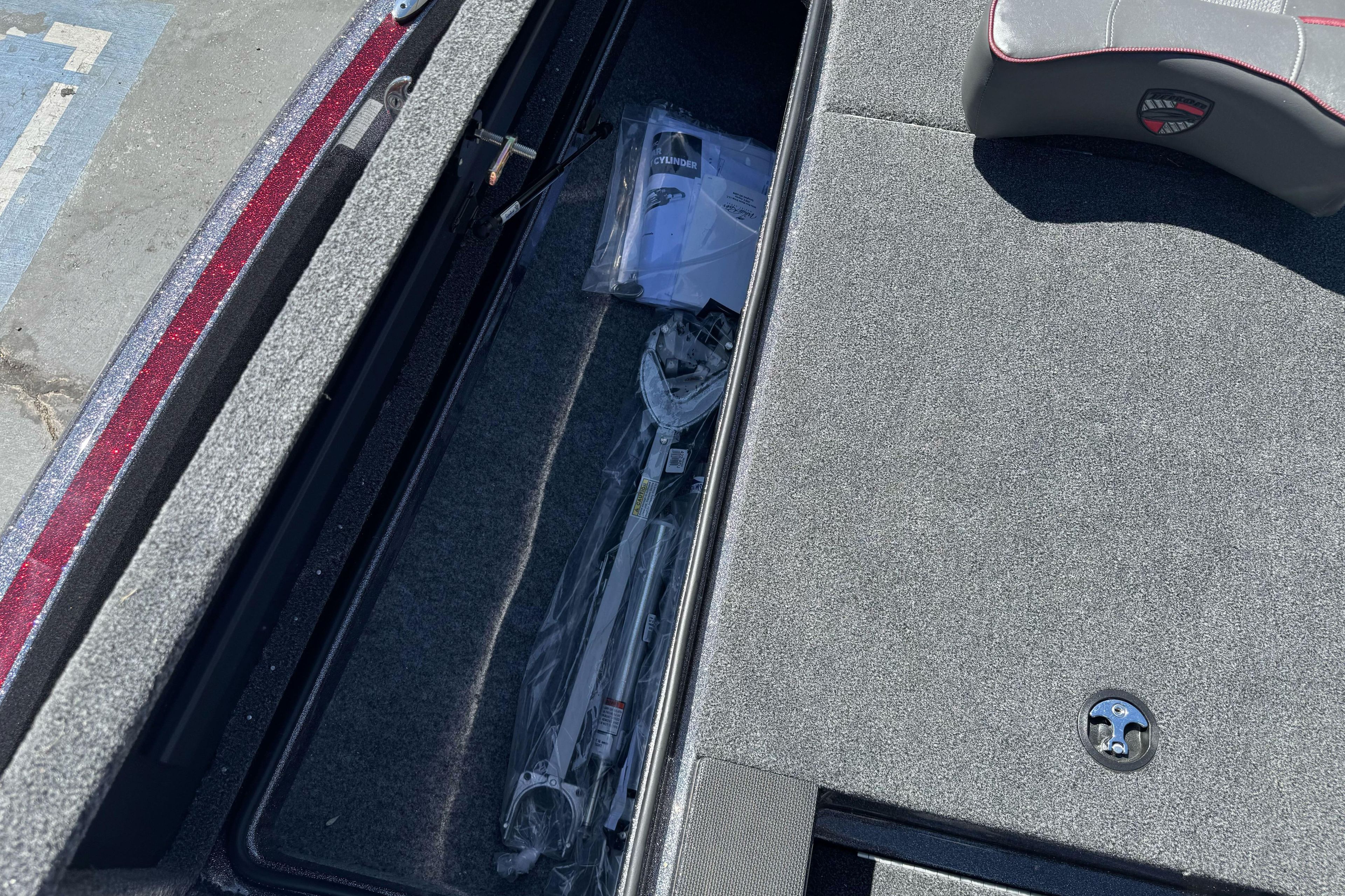 Storage compartment of 2026 Triton 18 TrX boat with equipment and manuals.