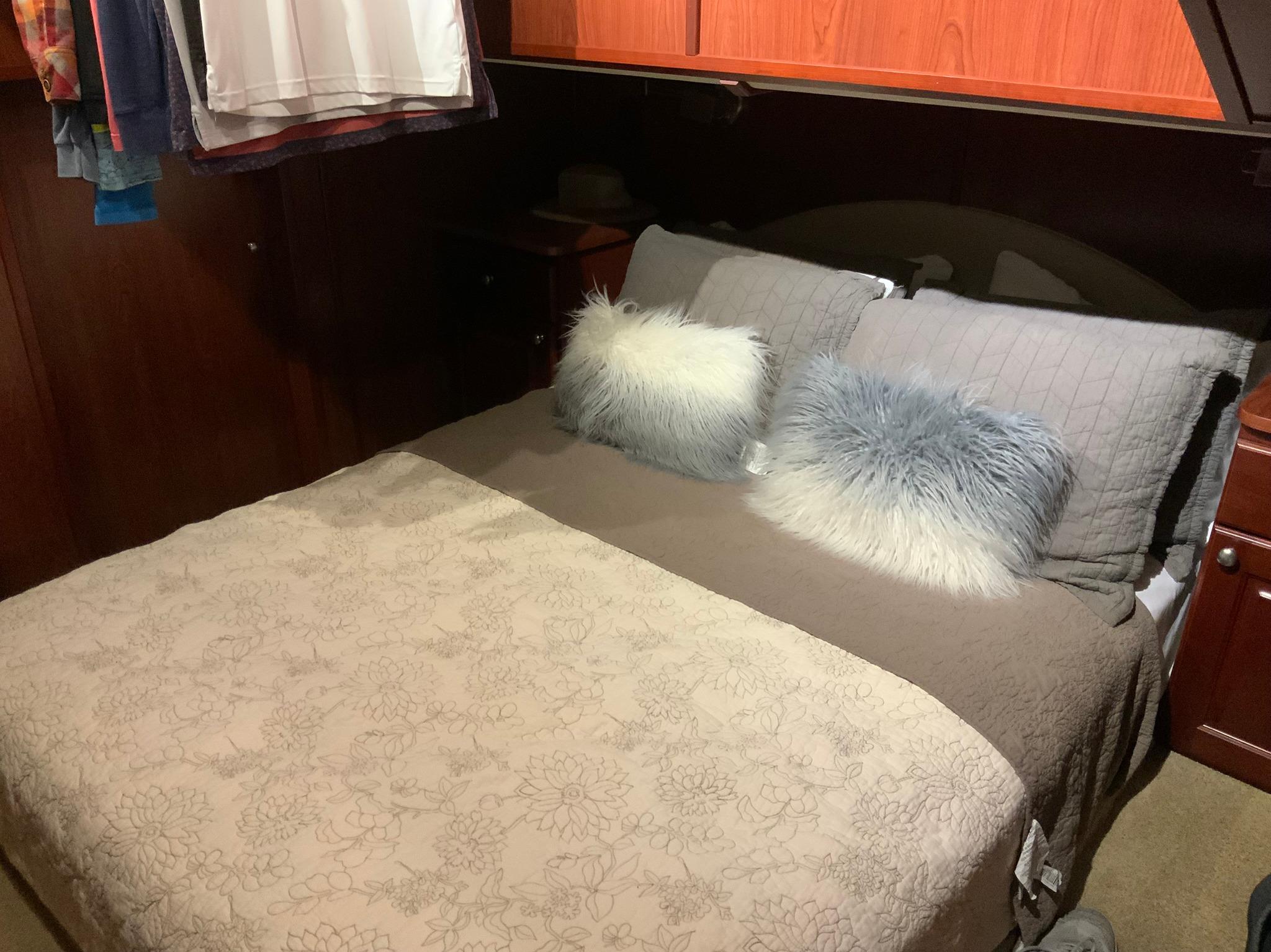Cozy bedroom interior of 2007 Skipperliner 640 with plush pillows and wooden accents.