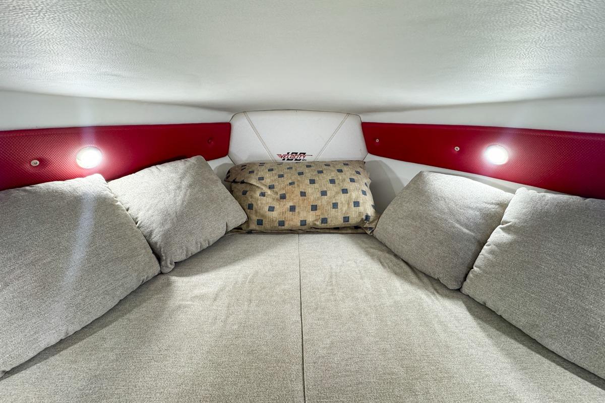 Cozy interior cabin of 2022 Velocity 290sc boat with cushions and ambient lighting.