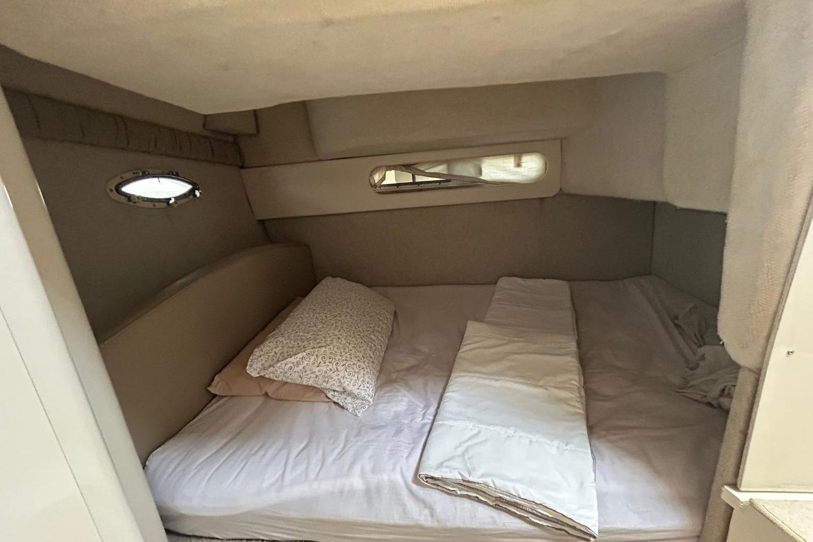 Cozy cabin interior of 2004 Bayliner 3055 Ciera with bed and porthole windows.