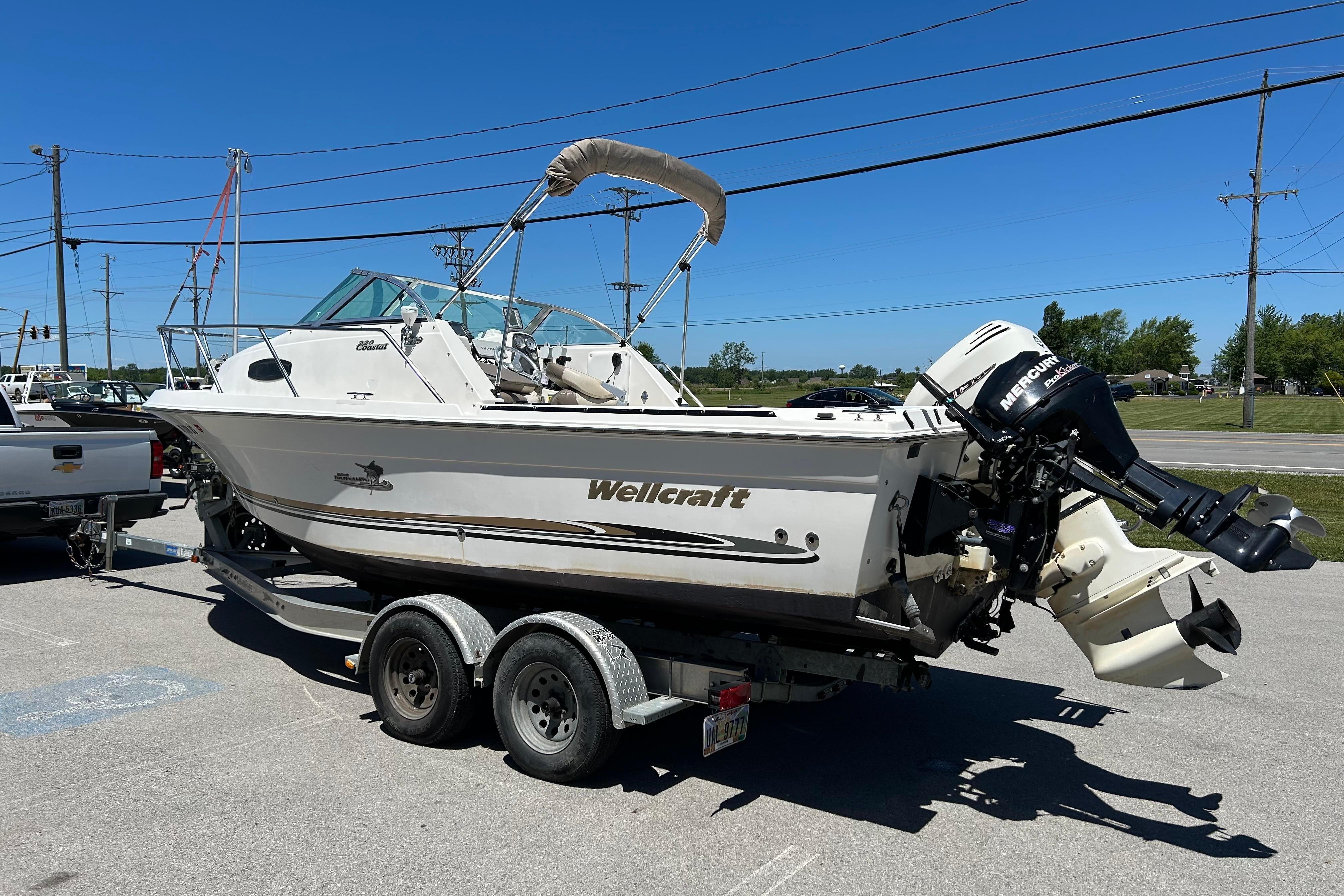 2003 Wellcraft 220 Coastal boat on trailer with outboard motor, parked outdoors.