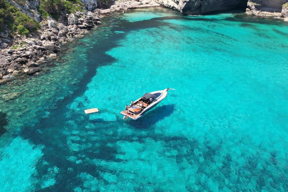 Aerial view of 2022 SAY 42 Open yacht in clear turquoise waters near rocky coastline.