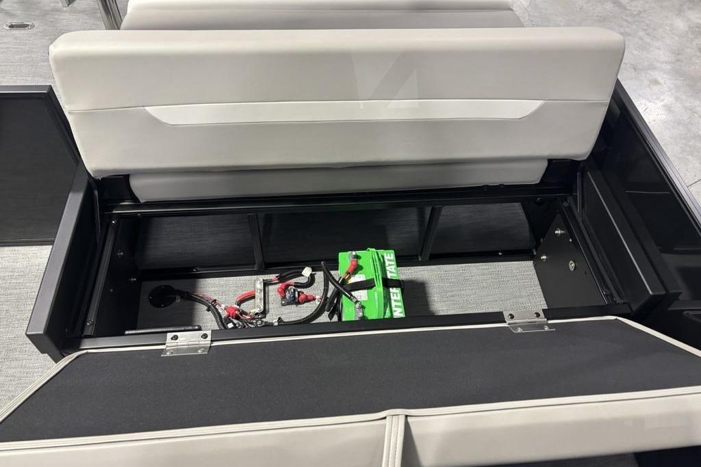 Open storage compartment in 2026 Godfrey Xperience 2086 SFLX boat, revealing battery and wiring.