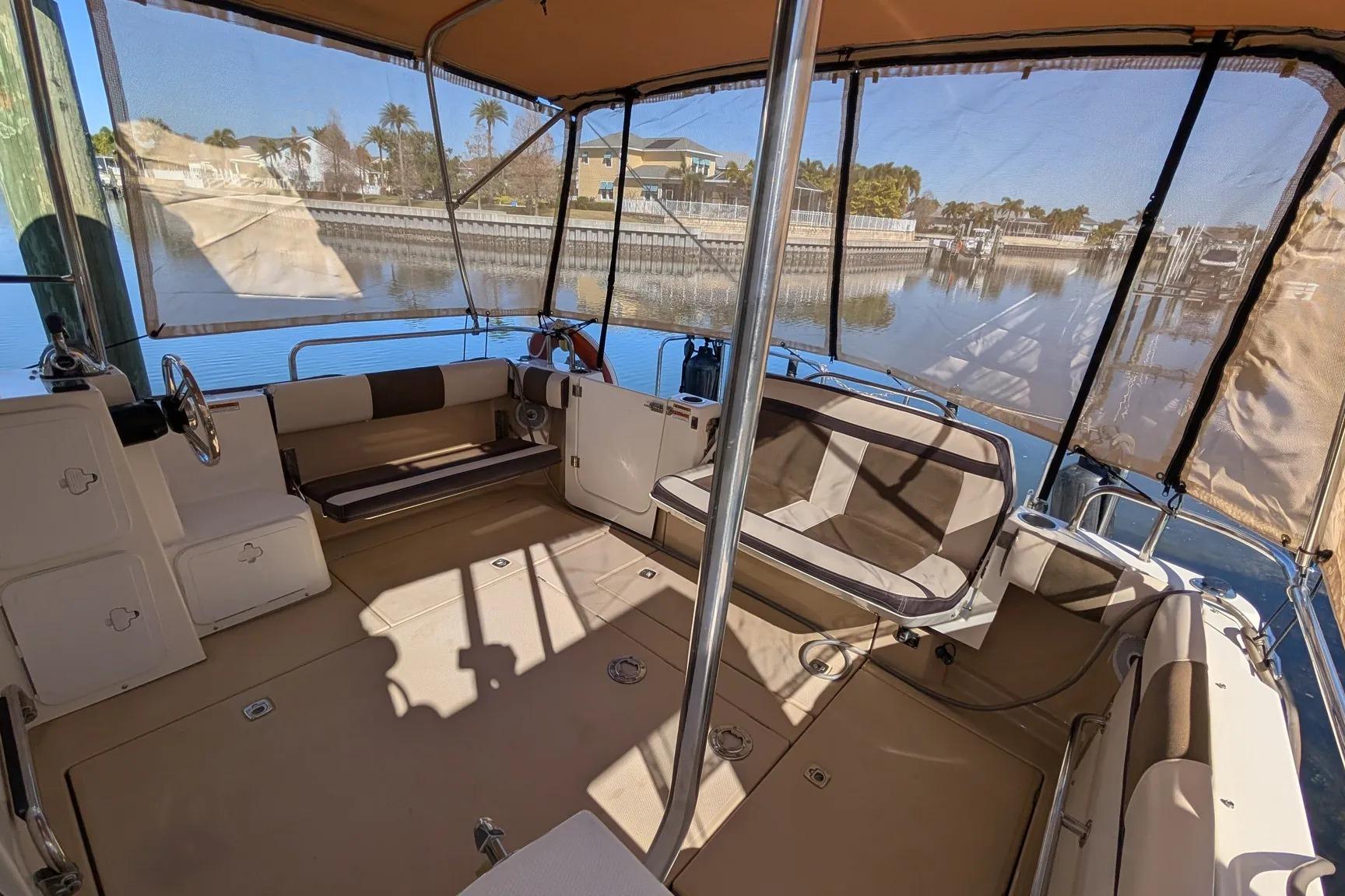 2015 Ranger Tugs R-29 S boat interior with seating and canopy, docked by calm waters.