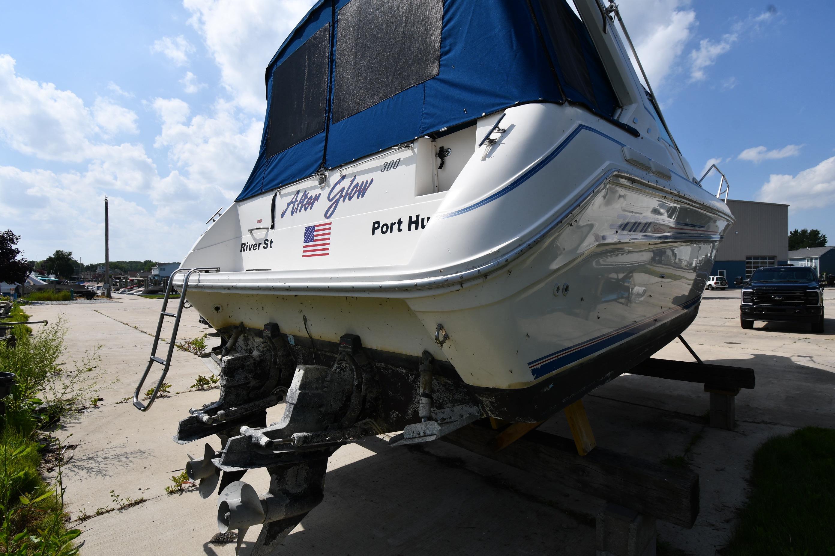 1993 Sea Ray 300 Sundancer boat on dry dock, featuring blue canopy and dual propellers.