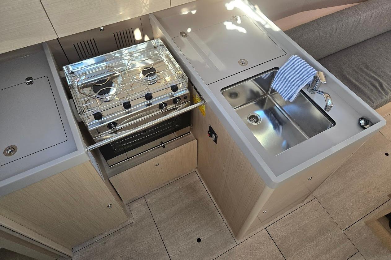 Modern kitchen area in 2023 Beneteau Oceanis 38.1 yacht with stove and sink.
