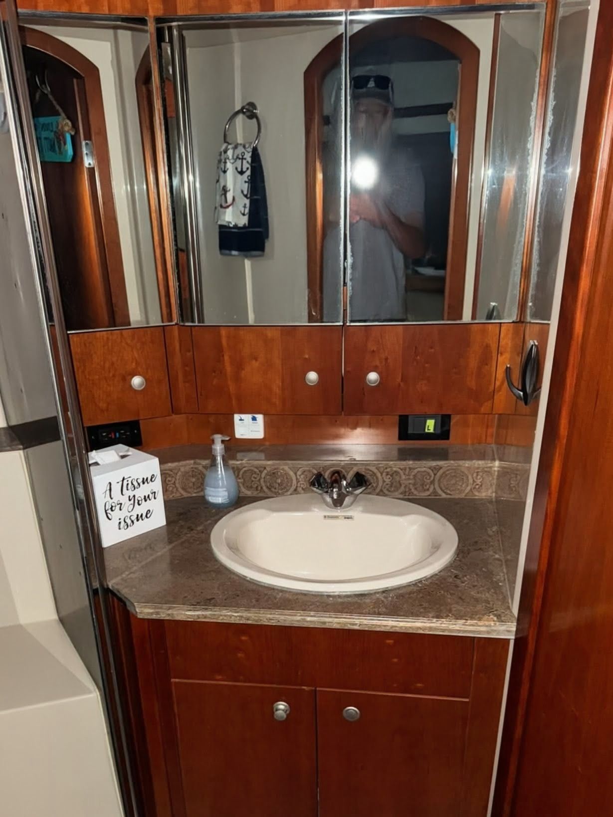 Bathroom with wooden cabinets, mirrors, and a sink with a marble countertop.