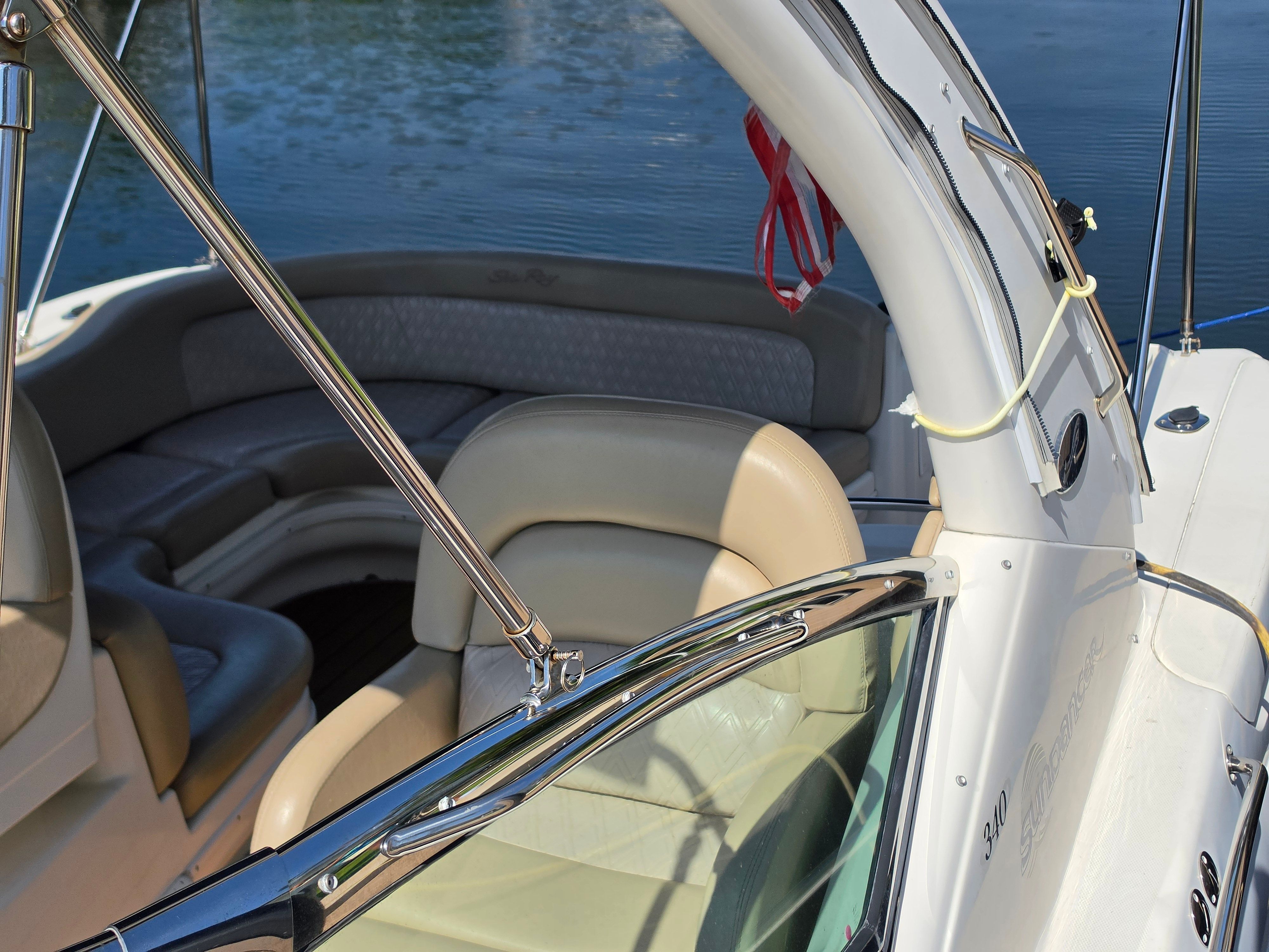 The image shows the cockpit of a 2004 Sea Ray 340 Sundancer with beige seating.