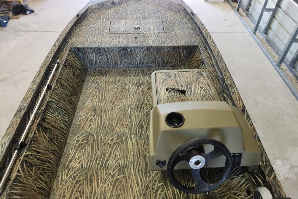 2026 Tracker Grizzly 1648 SC boat with camouflage interior design in a garage setting.