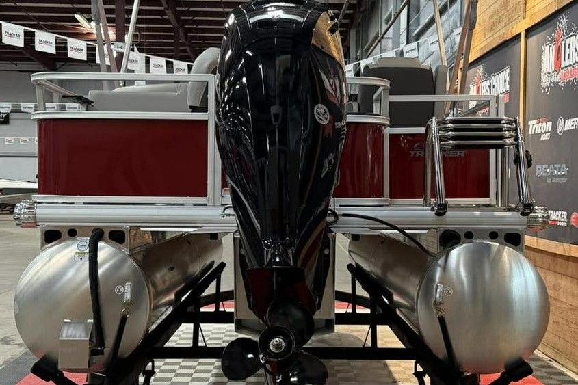 2026 Sun Tracker Bass Buggy 18 DLX pontoon boat with outboard motor in showroom.