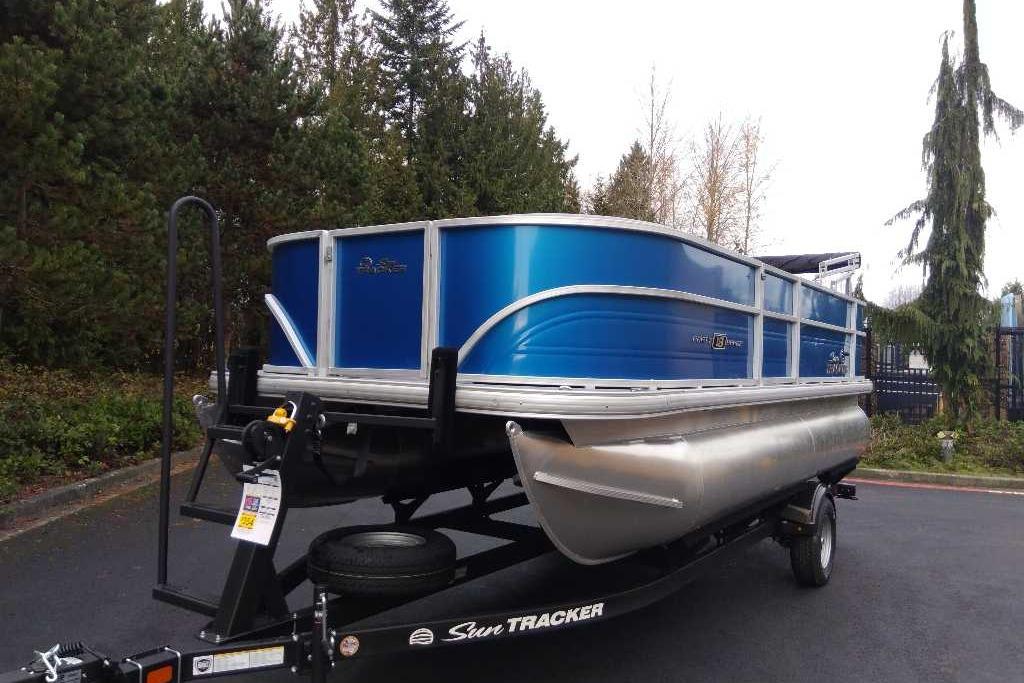 2026 Sun Tracker Party Barge 18 DLX pontoon boat on trailer, parked outdoors.