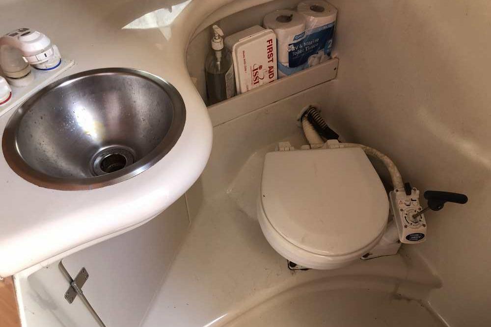 1999 Regal Commodore 2760 boat bathroom with sink, toilet, and storage shelves.