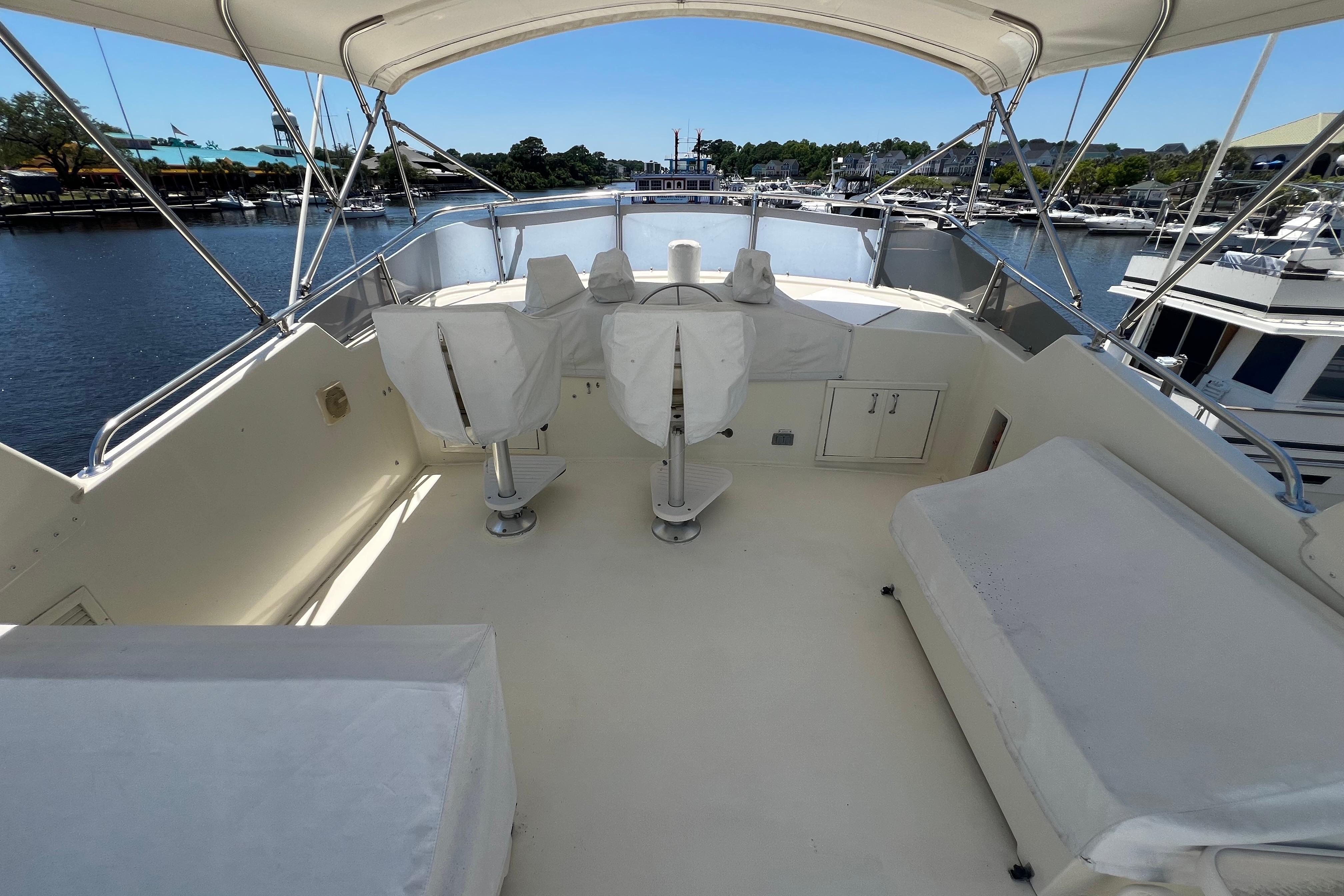 1987 Hatteras 70 Cockpit Motor Yacht flybridge with covered seating and helm chairs.