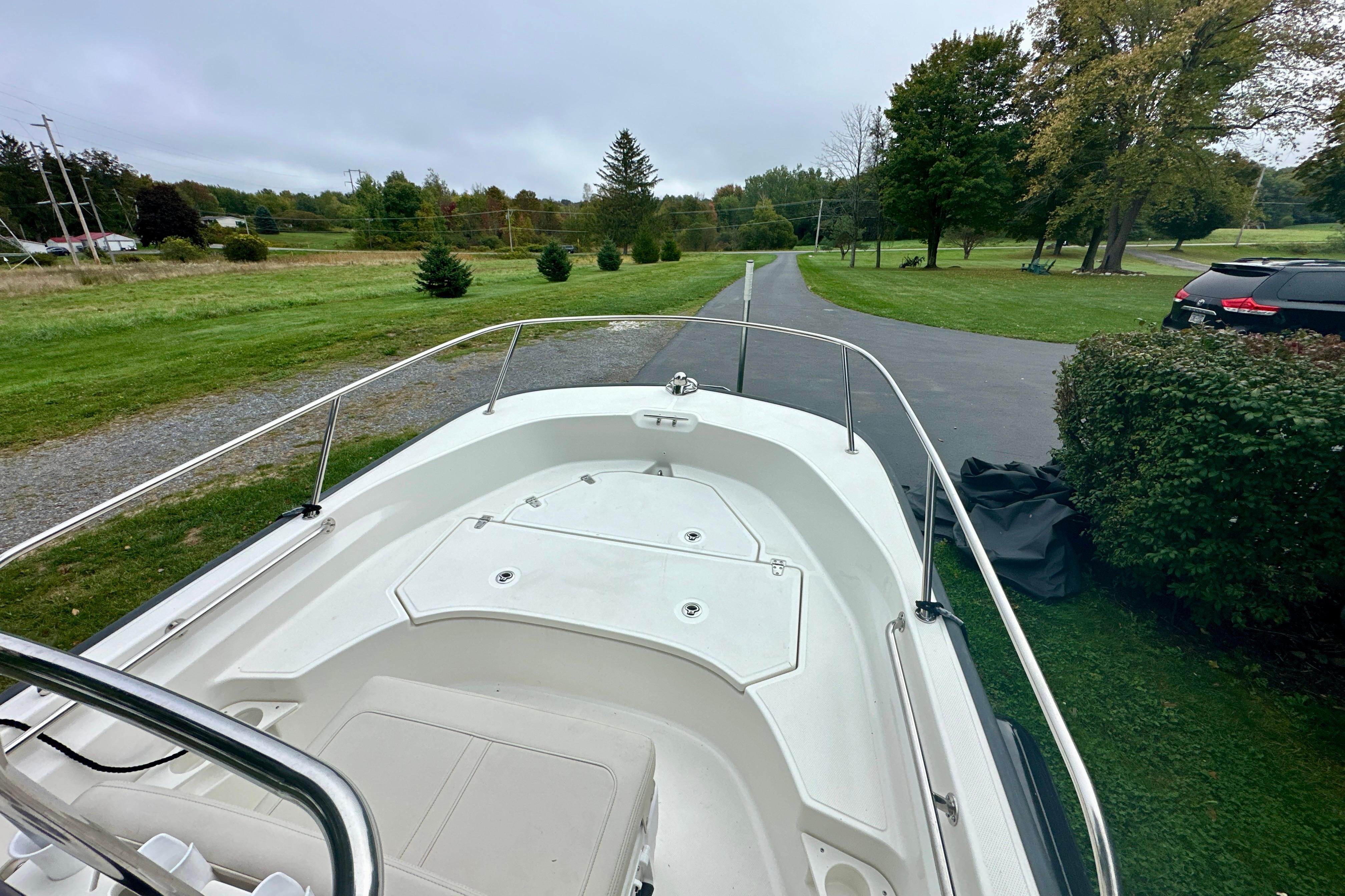 2024 Boston Whaler 170 Montauk boat on a driveway, surrounded by greenery.